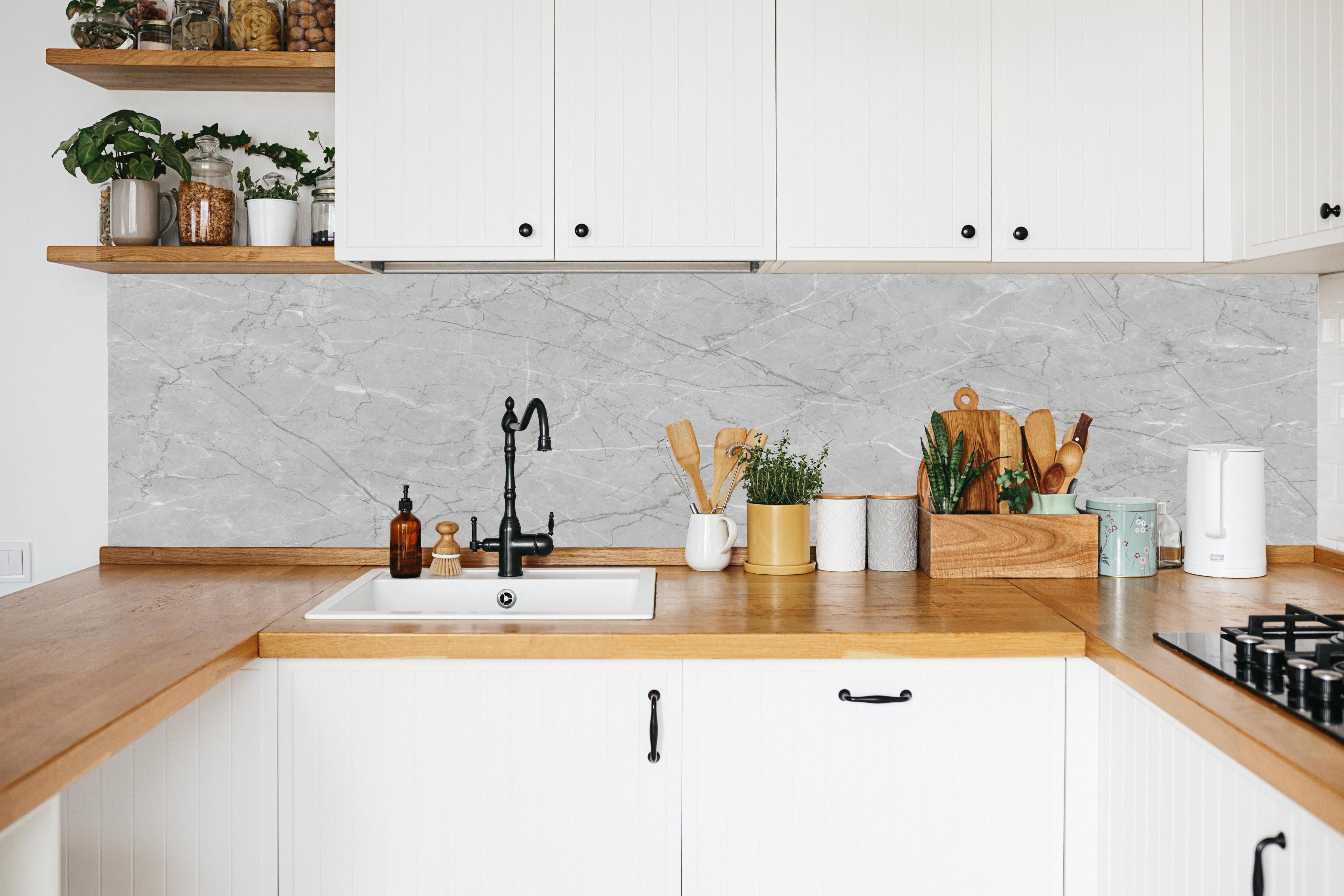 Küche - Minimalistische Marmorfläche in Weiß und Grau in weißer Küche hinter Gewürzen und Kochlöffeln aus Holz