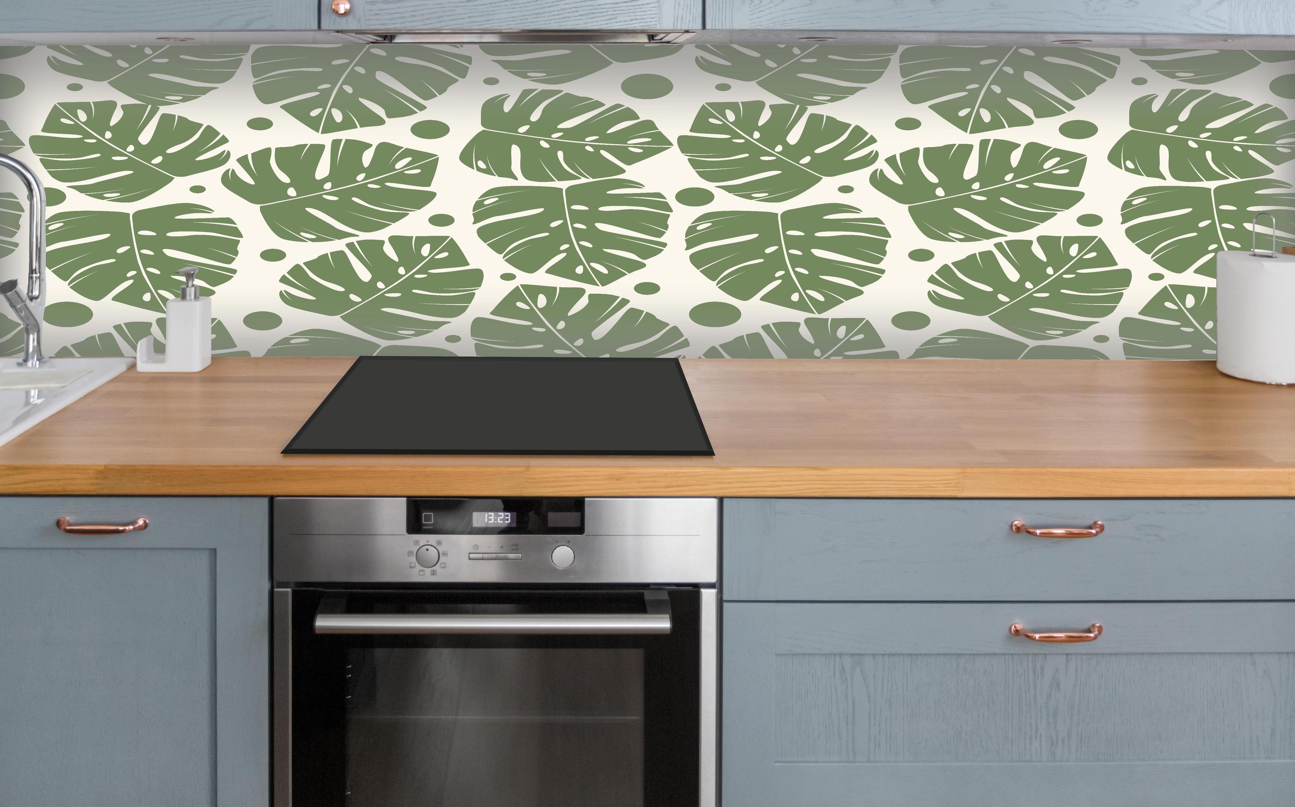 Küche - Monstera-Blätter Cremegrün über polierter Holzarbeitsplatte mit Cerankochfeld