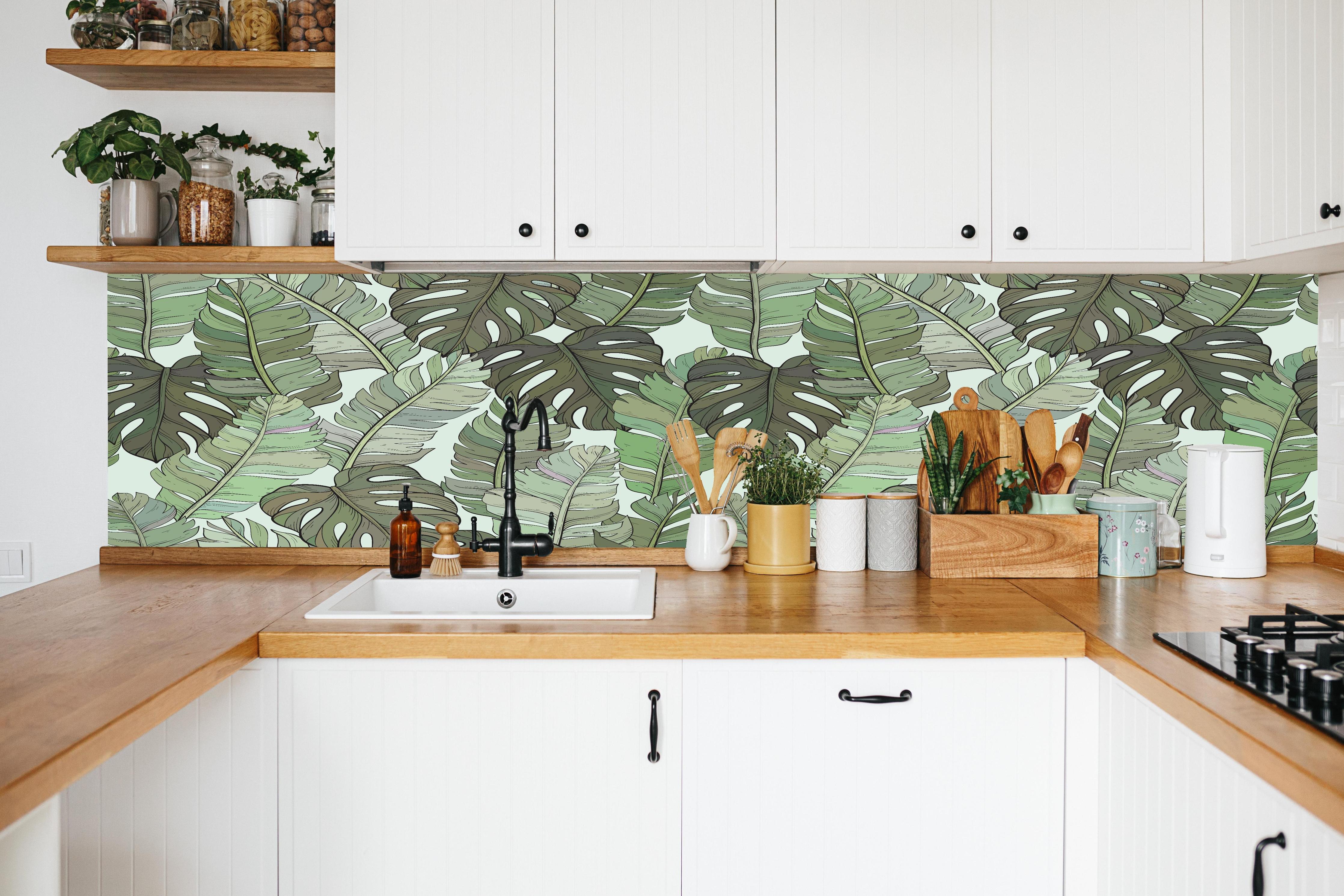 Küche - Monstera-Blätter – Tropische Eleganz in weißer Küche hinter Gewürzen und Kochlöffeln aus Holz