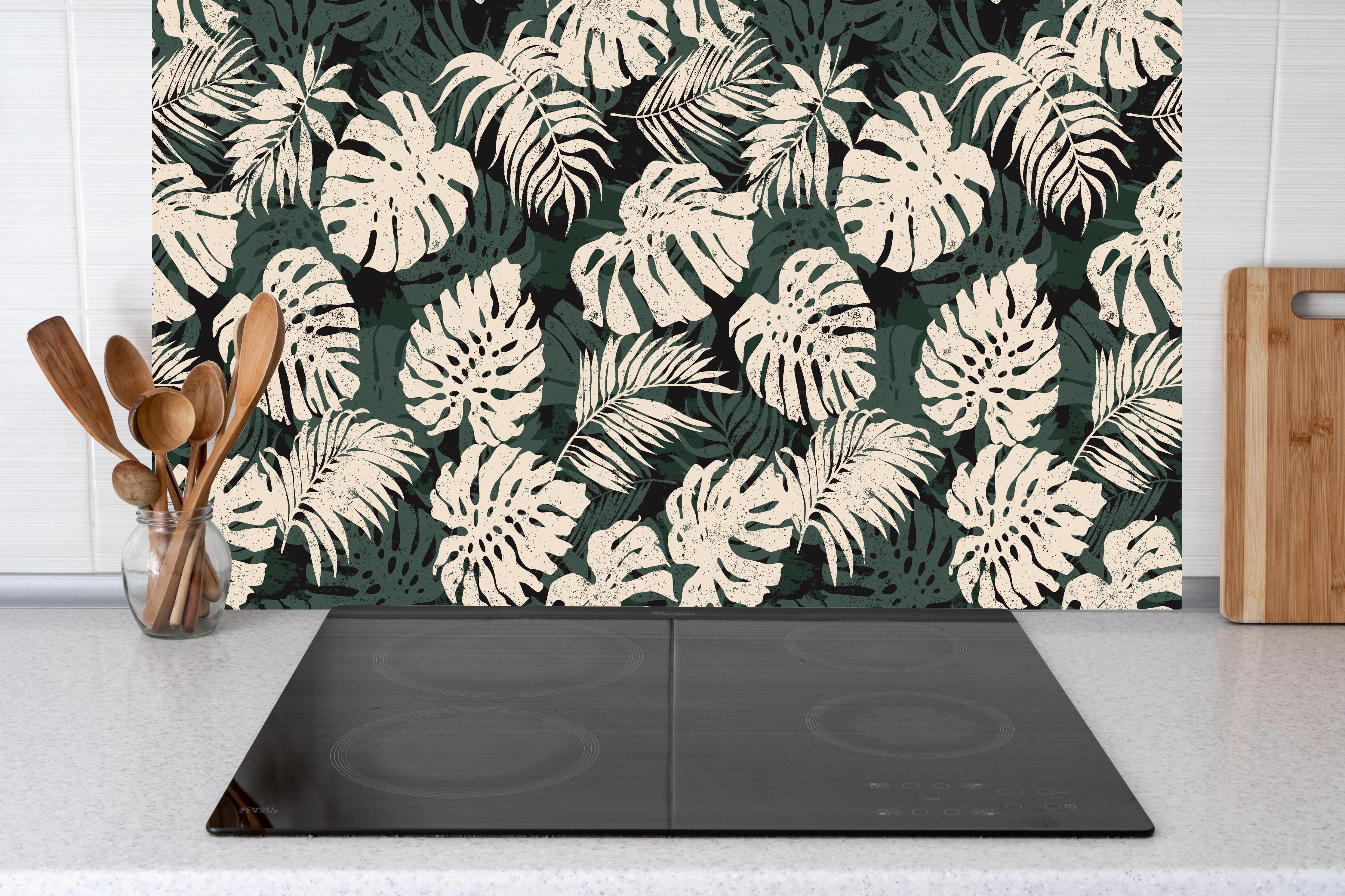 Küche - Monstera Blattmuster Grün-Beige hinter Cerankochfeld und Holz-Kochutensilien