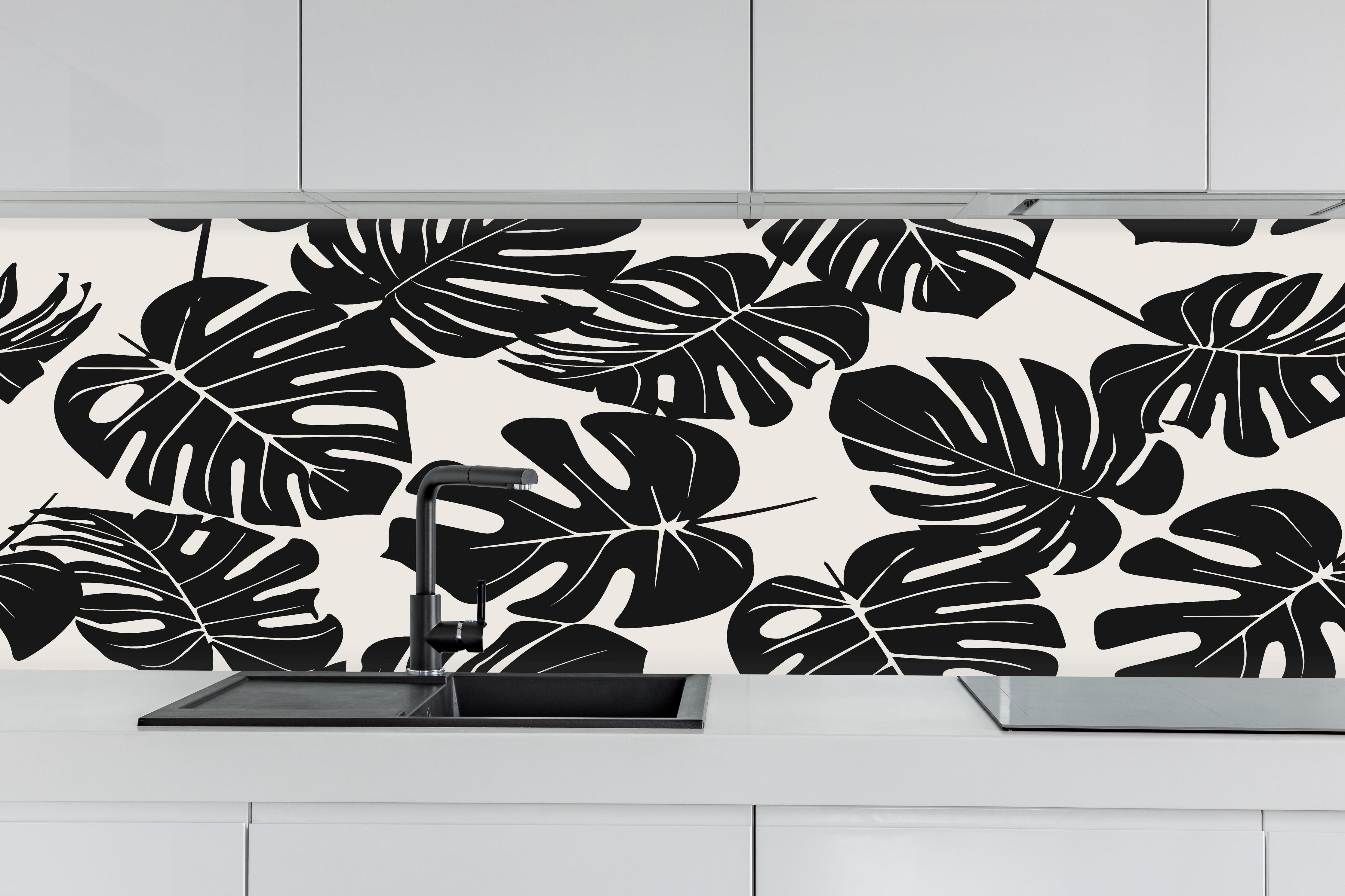 Küche - Monstera Schwarz-Beige Muster hinter weißen Hochglanz-Küchenregalen und schwarzem Wasserhahn