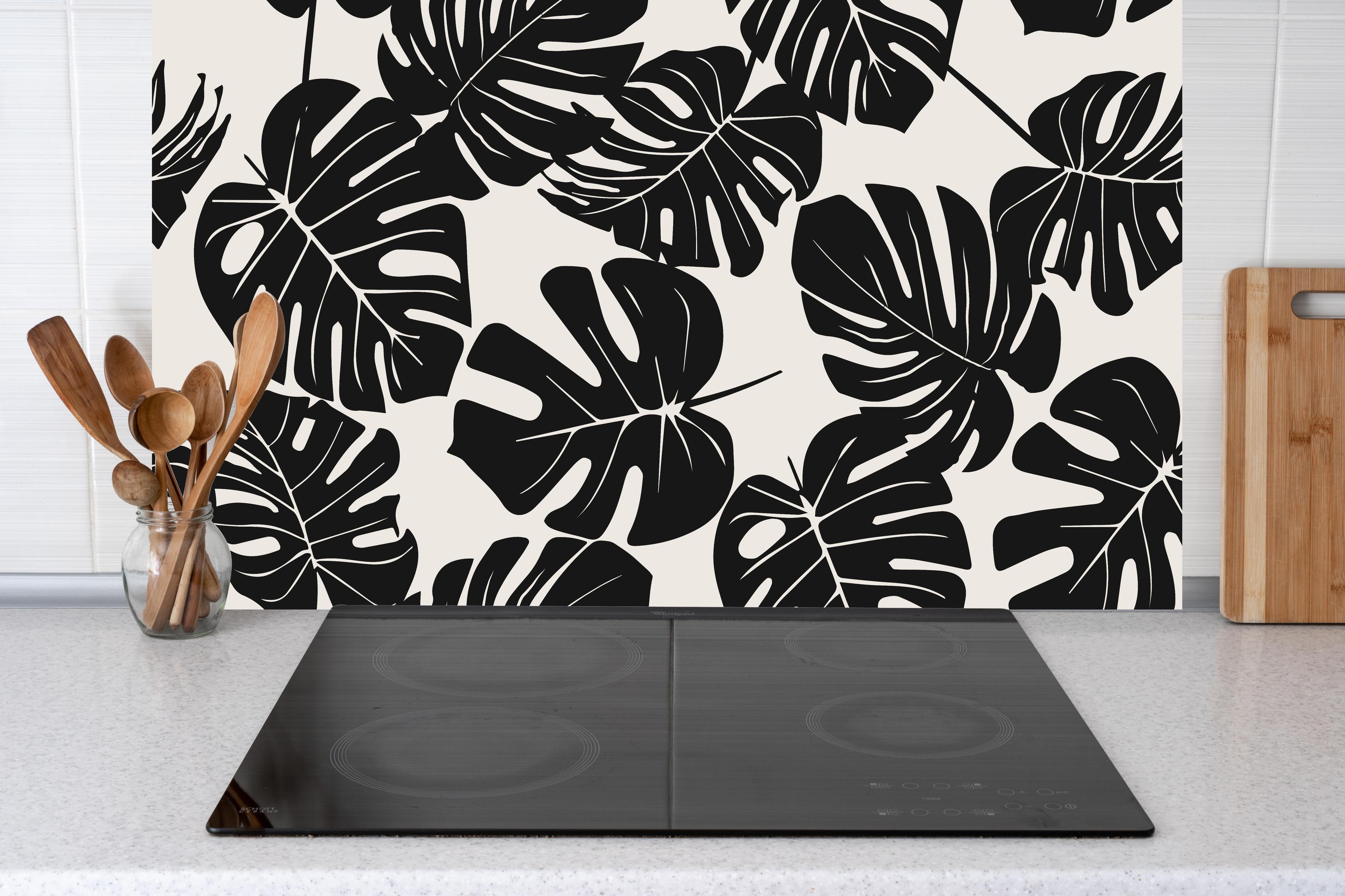 Küche - Monstera Schwarz-Beige Muster hinter Cerankochfeld und Holz-Kochutensilien