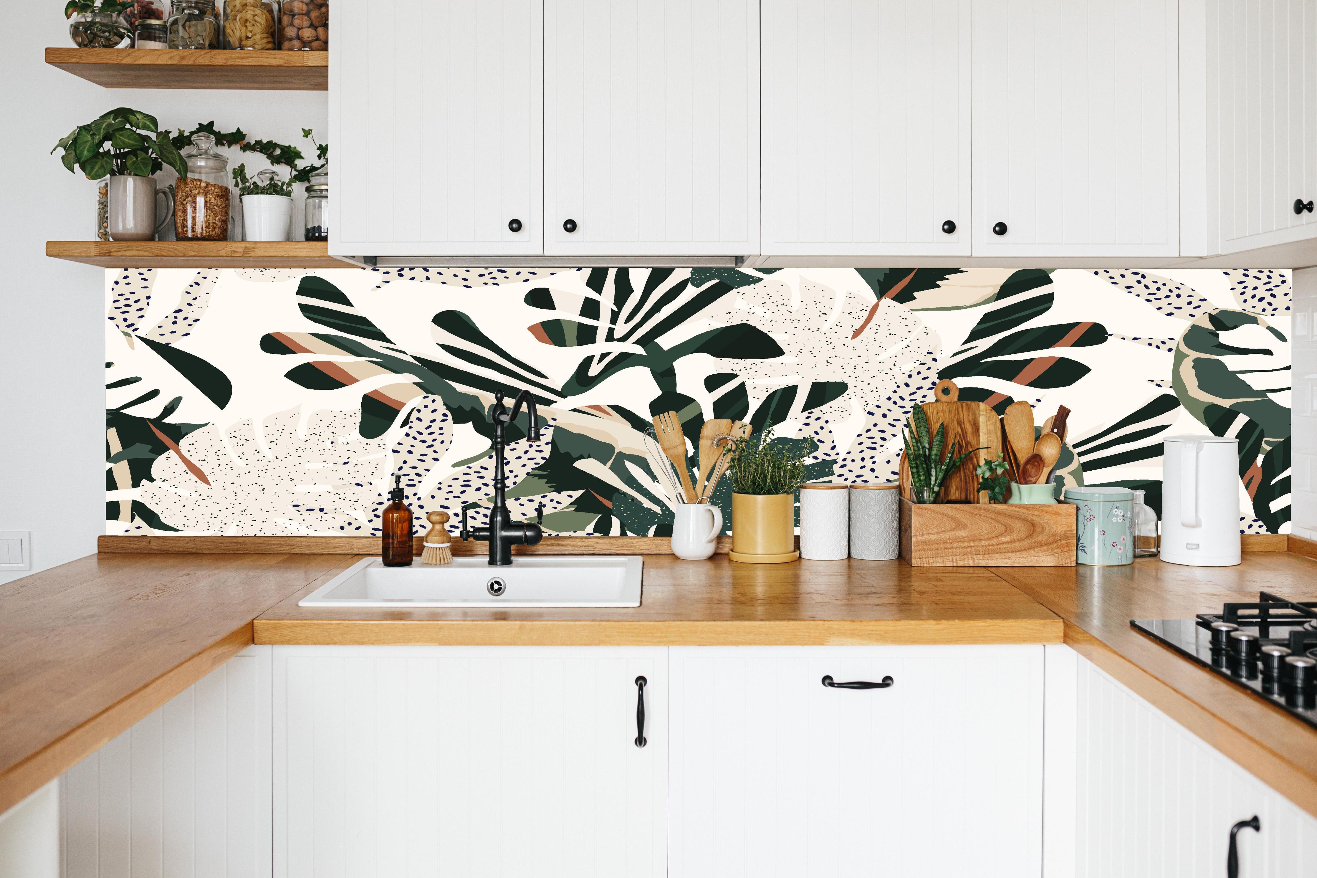 Küche - Monstera Tropic Grün-Beige in weißer Küche hinter Gewürzen und Kochlöffeln aus Holz