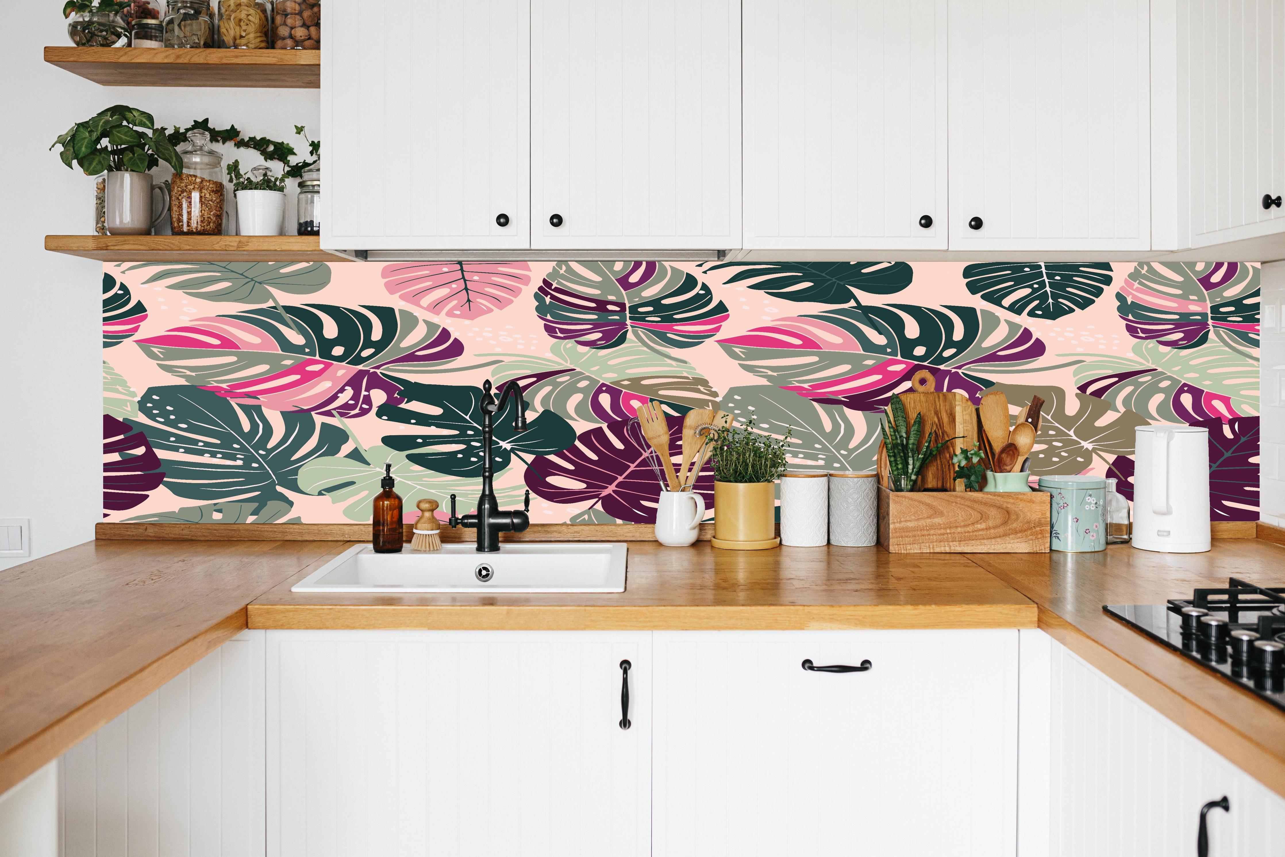 Küche - Monstera Tropic Rosa-Grün in weißer Küche hinter Gewürzen und Kochlöffeln aus Holz