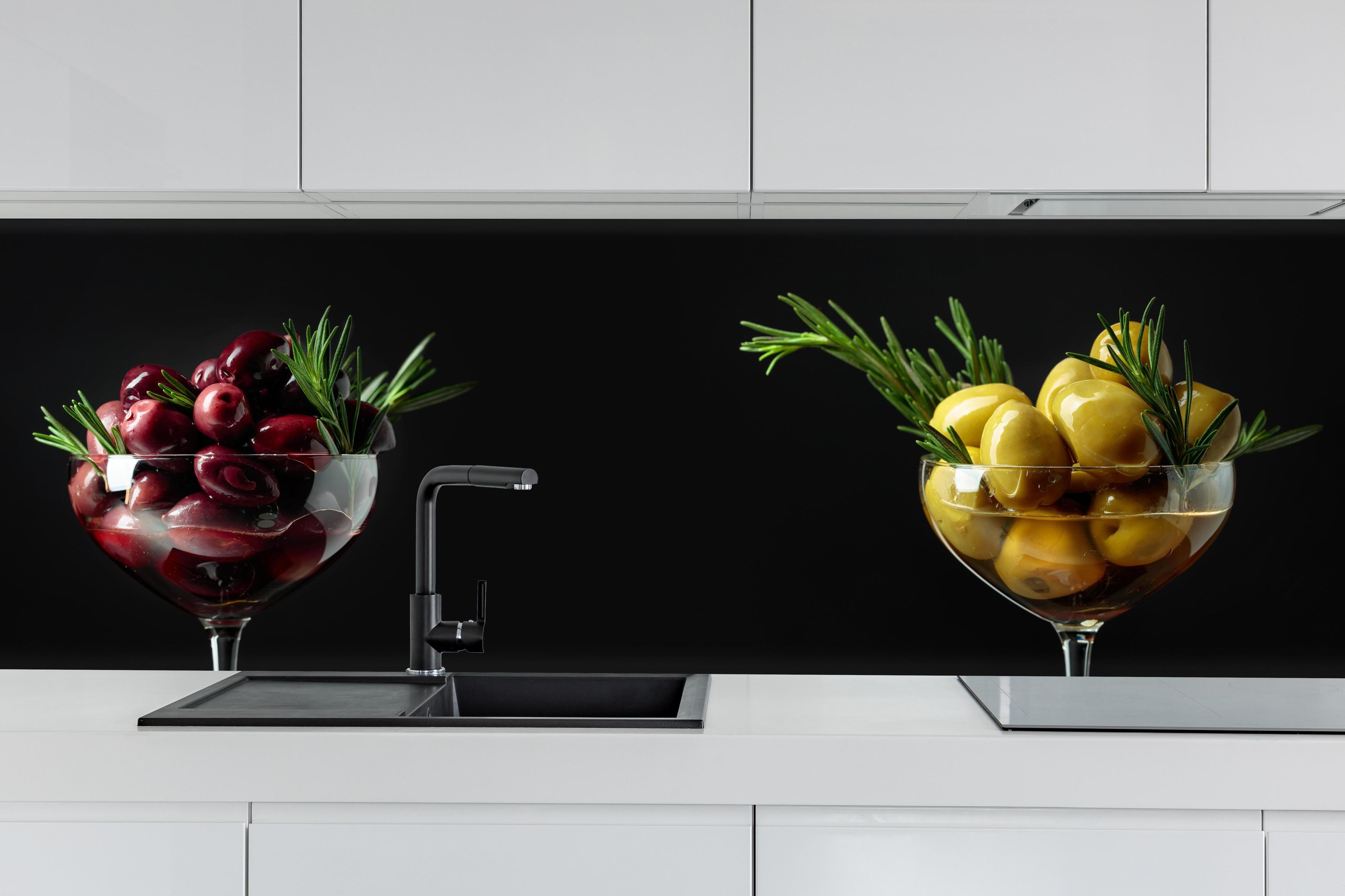 Küche - Oliven-Duo Rot und Gelb hinter weißen Hochglanz-Küchenregalen und schwarzem Wasserhahn