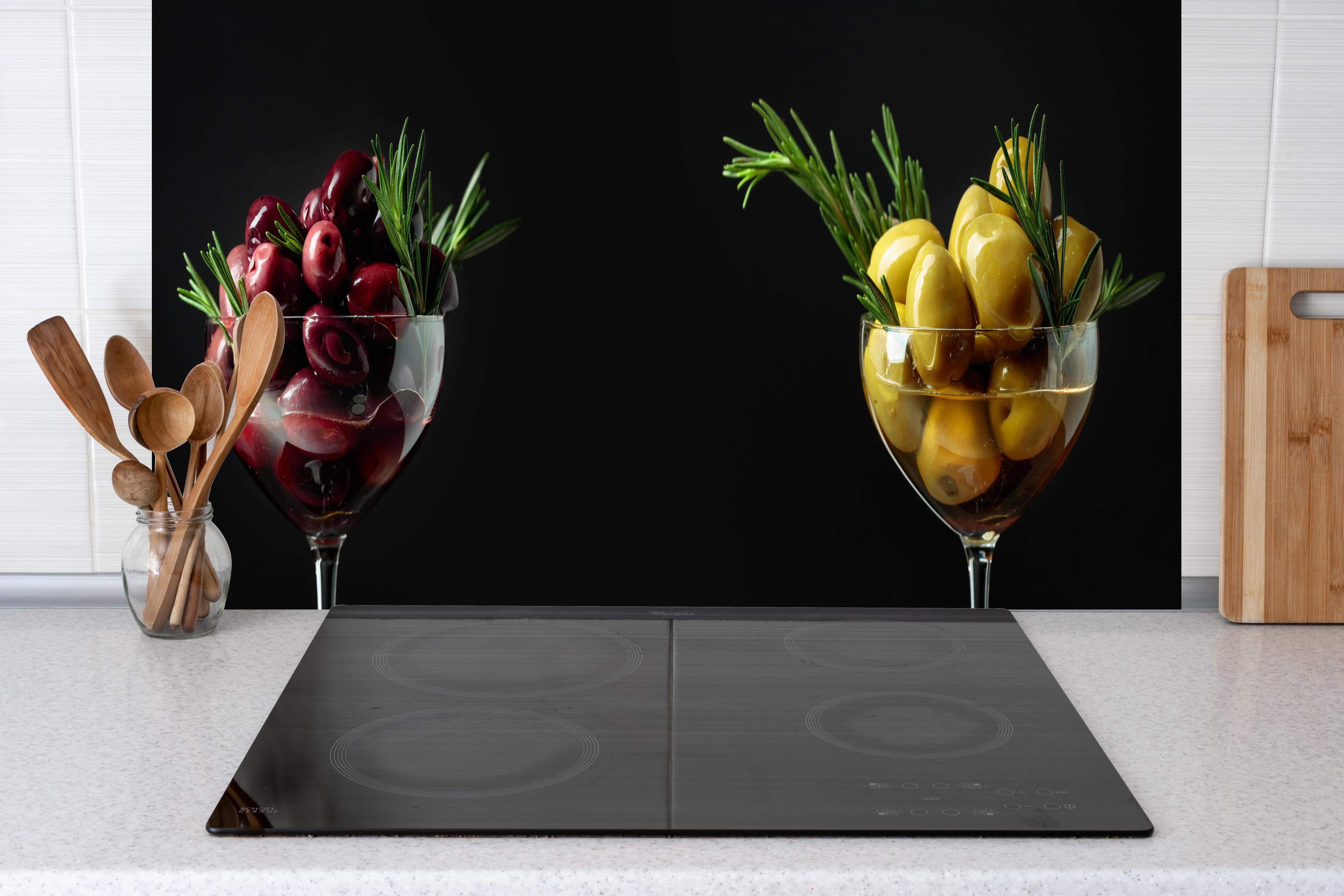 Küche - Oliven-Duo Rot und Gelb hinter Cerankochfeld und Holz-Kochutensilien