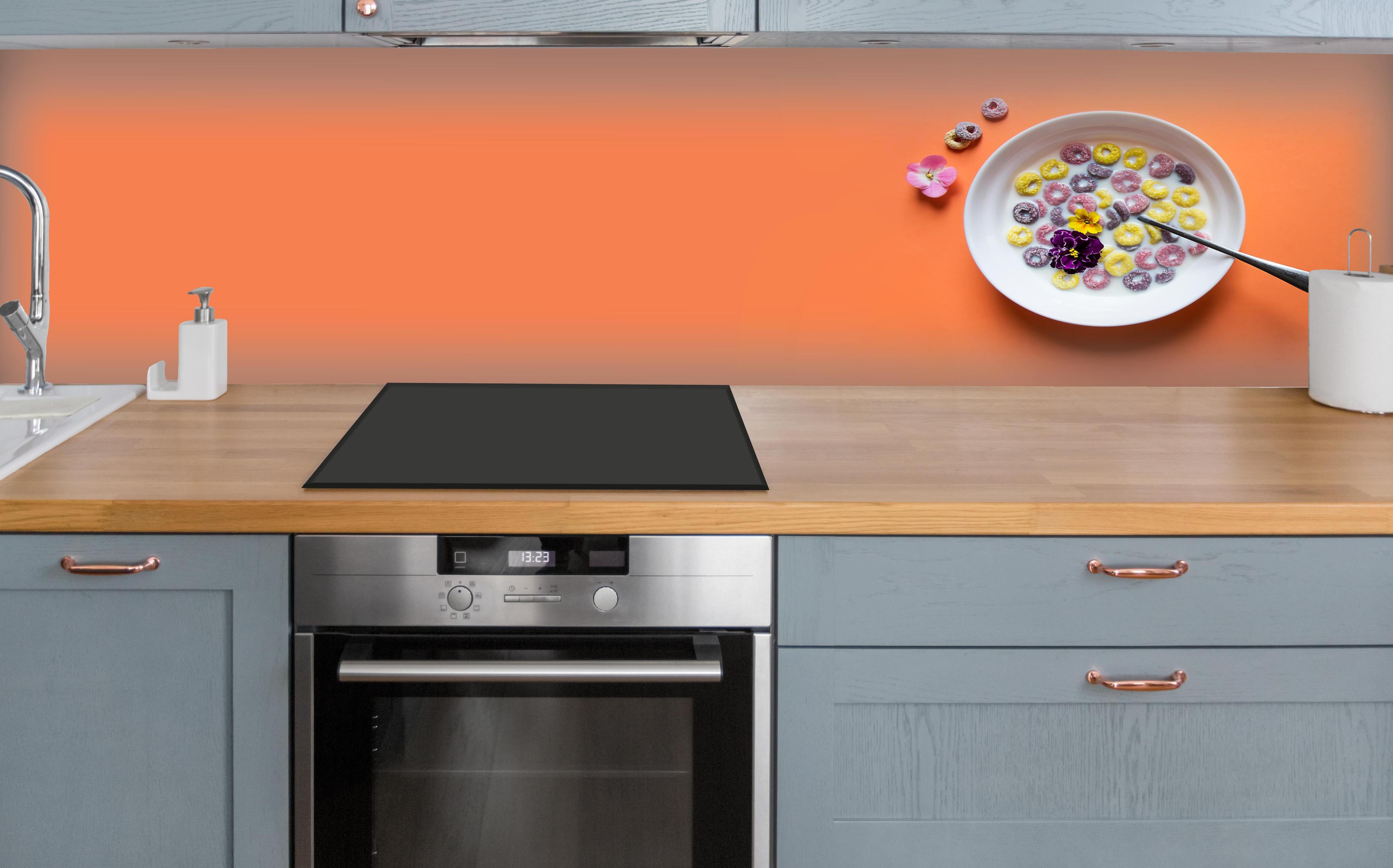 Küche - Orange Frühstücks-Bowl über polierter Holzarbeitsplatte mit Cerankochfeld