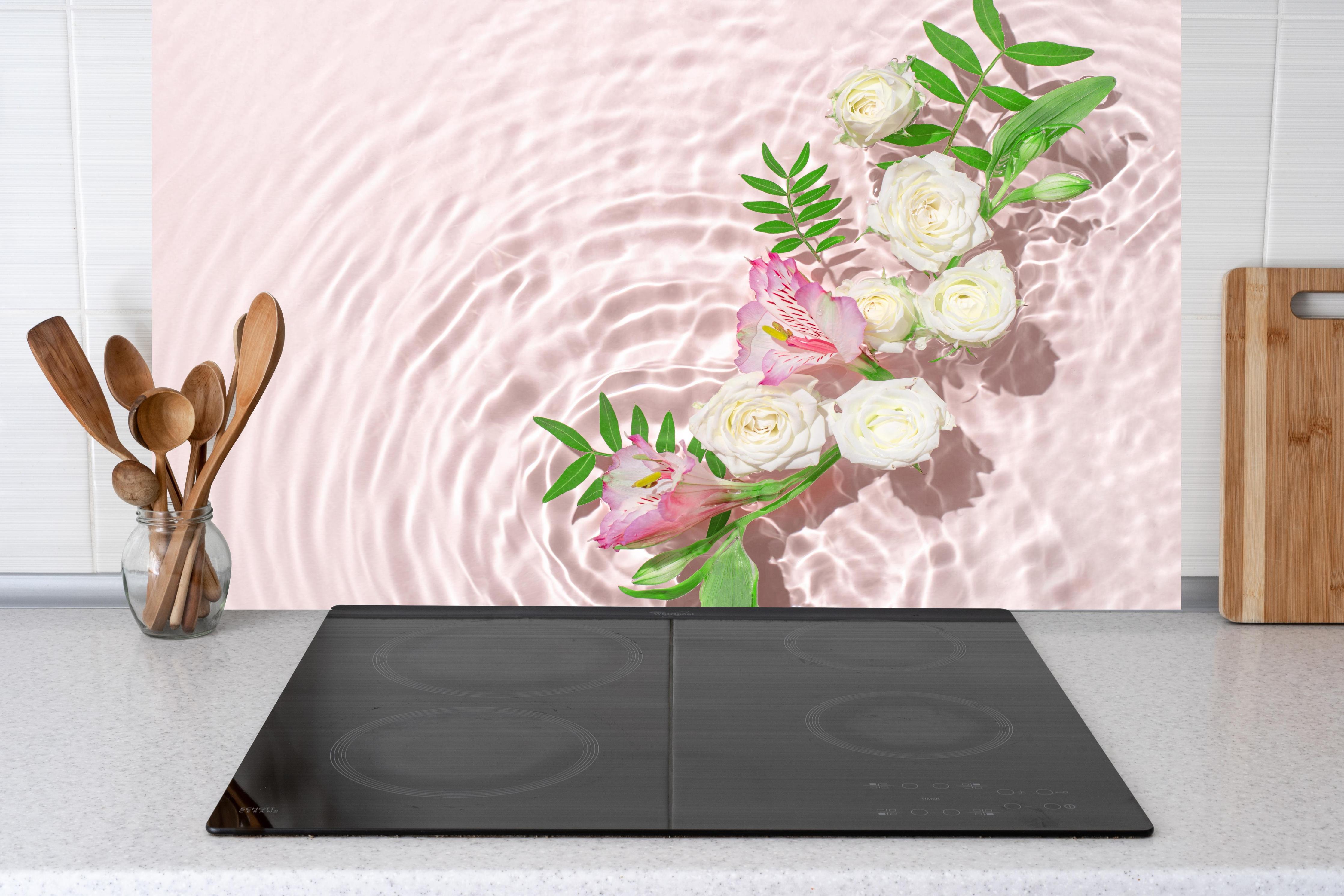 Küche - Rosa Blumen auf Wasser hinter Cerankochfeld und Holz-Kochutensilien