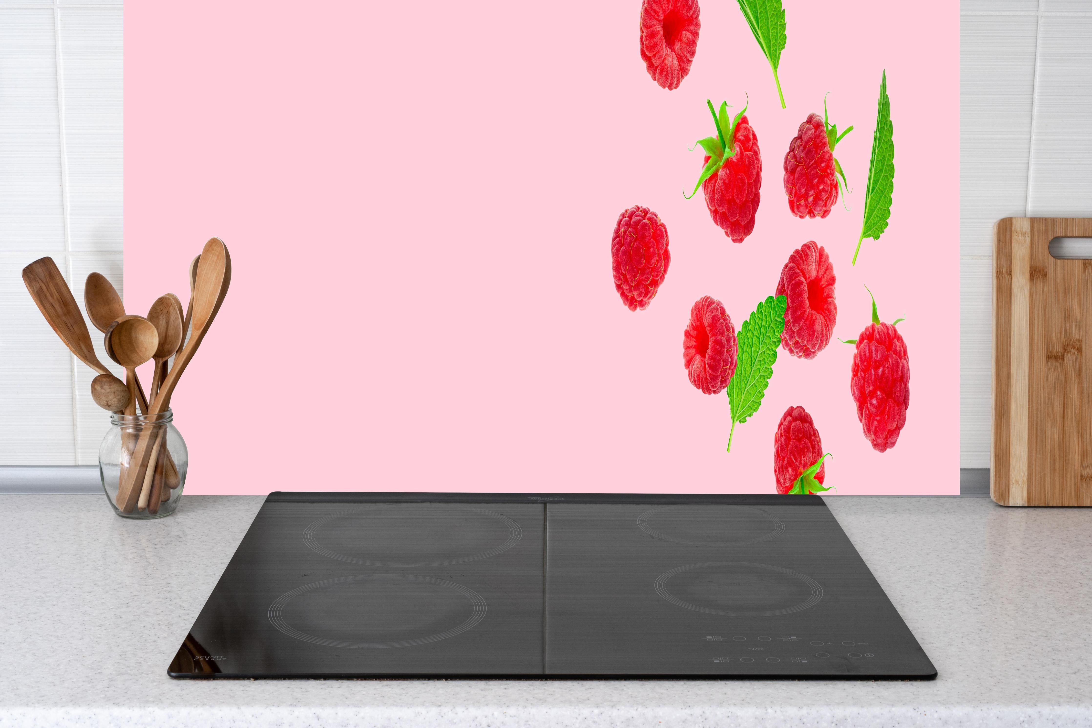 Küche - Rosa Himbeeren mit Minze hinter Cerankochfeld und Holz-Kochutensilien