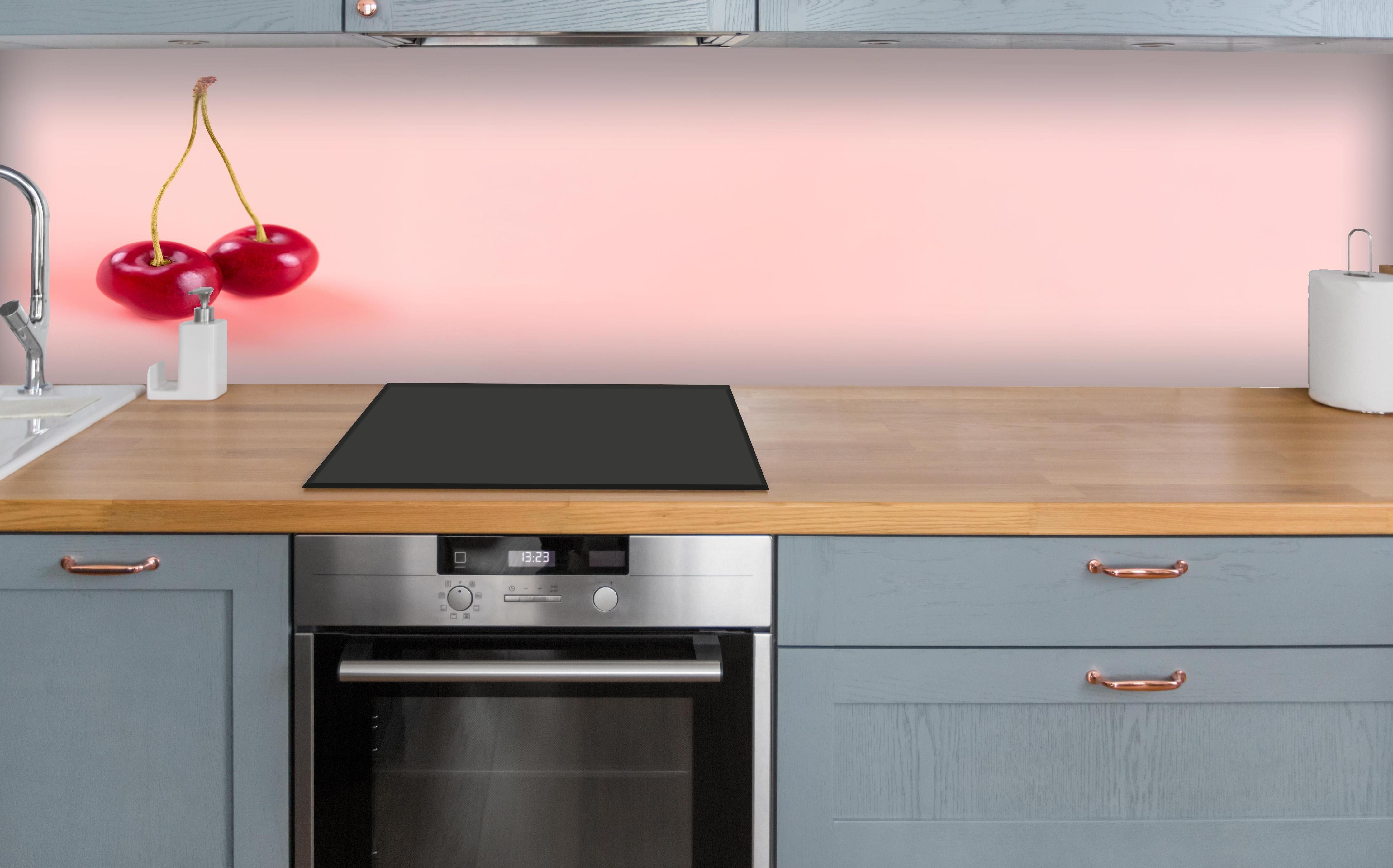 Küche - Rote Kirschen auf Rosa Hintergrund über polierter Holzarbeitsplatte mit Cerankochfeld