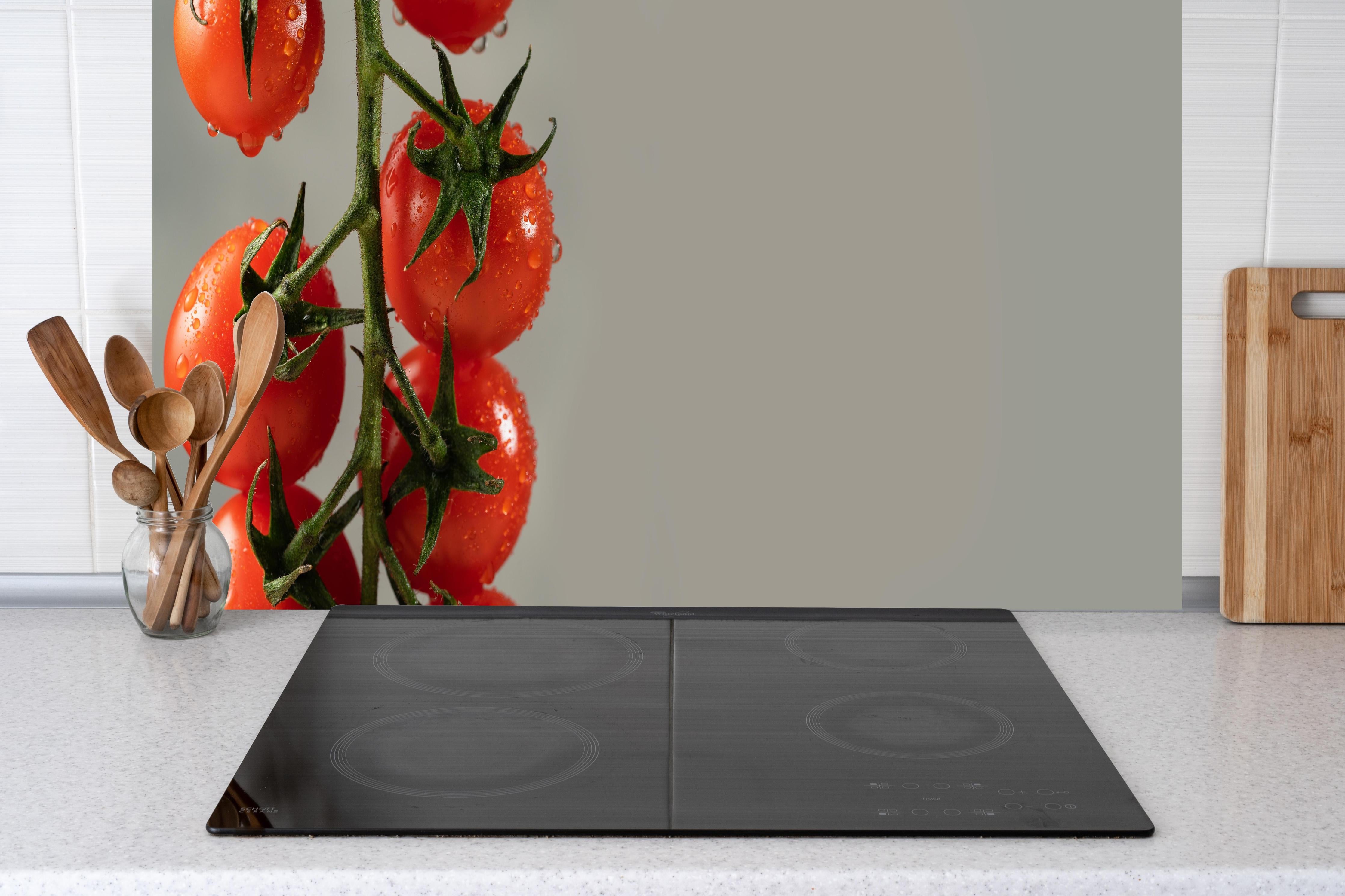 Küche - Rote Tomaten auf Grau hinter Cerankochfeld und Holz-Kochutensilien