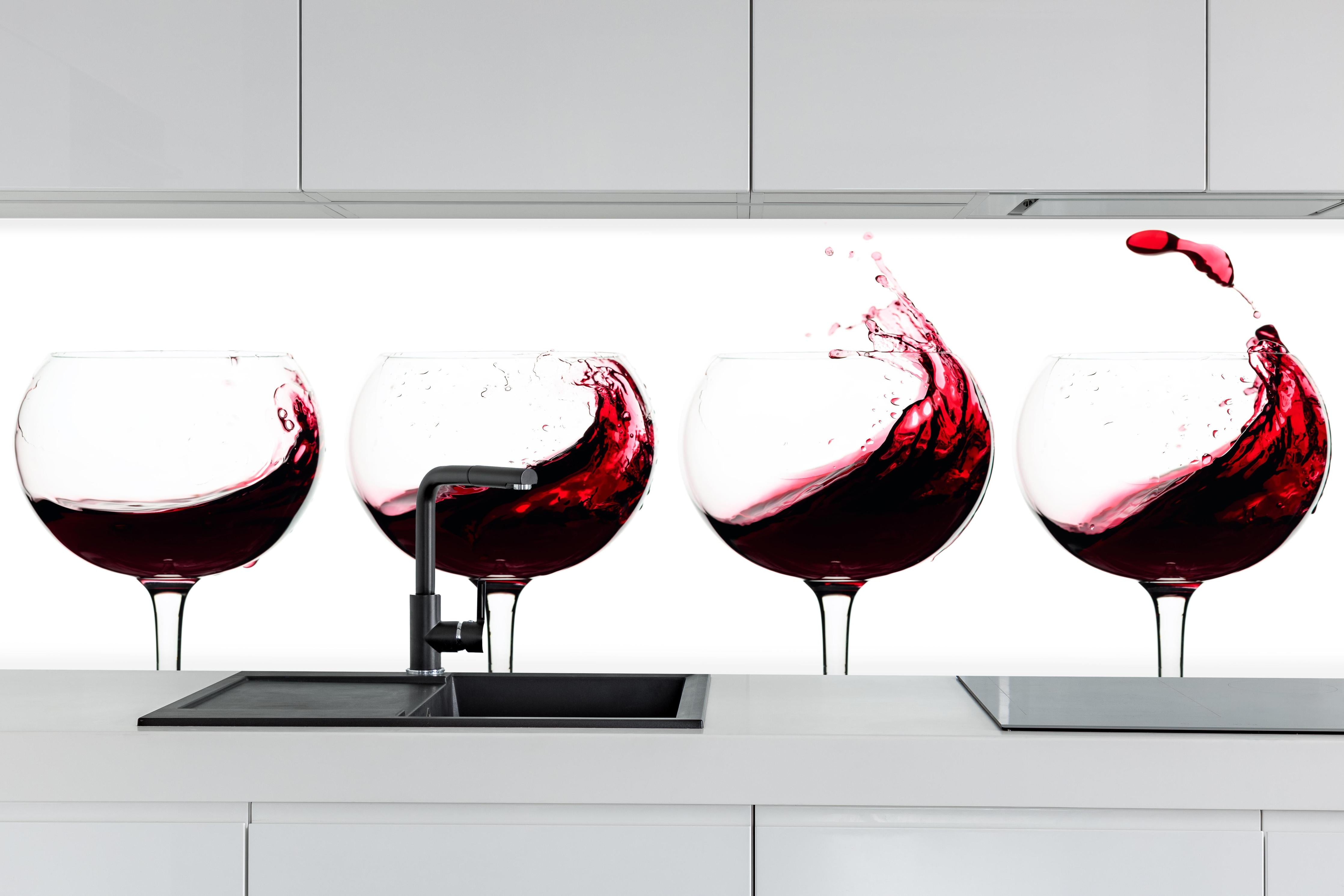 Küche - Rotwein-Splash in Weingläsern hinter weißen Hochglanz-Küchenregalen und schwarzem Wasserhahn
