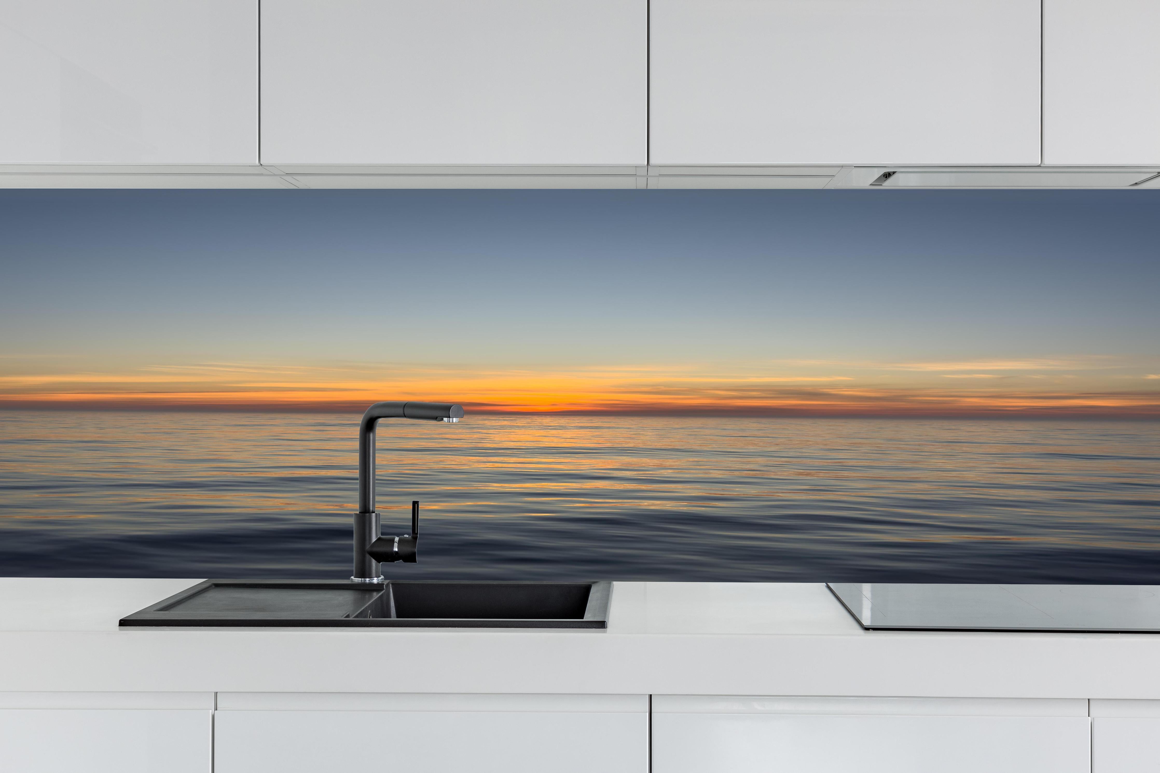 Küche - Sonnenuntergang über ruhigem Meer hinter weißen Hochglanz-Küchenregalen und schwarzem Wasserhahn