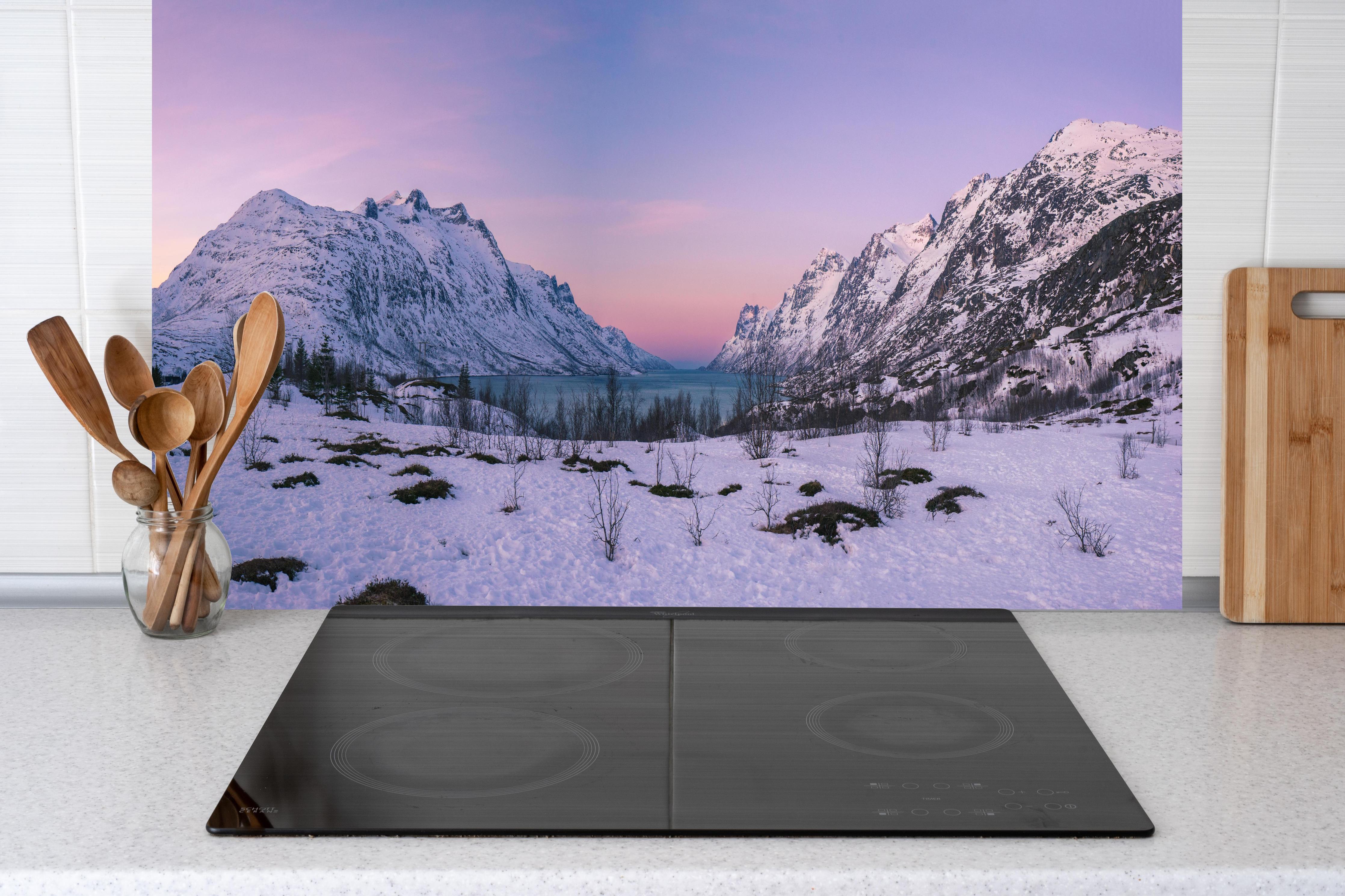 Küche - Sonnenuntergang über verschneiten Bergen hinter Cerankochfeld und Holz-Kochutensilien