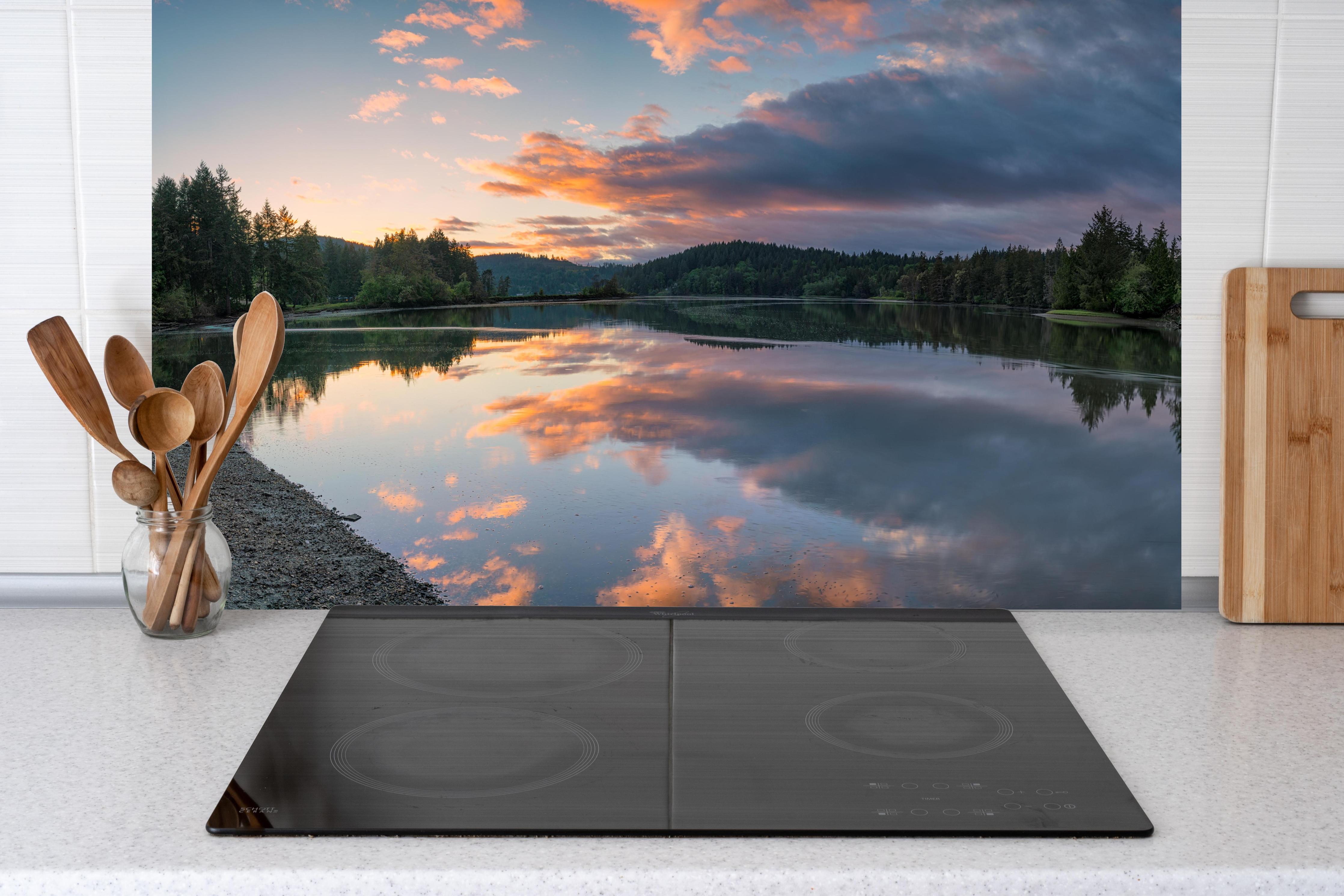 Küche - Spiegelnder See im Sonnenuntergang hinter Cerankochfeld und Holz-Kochutensilien