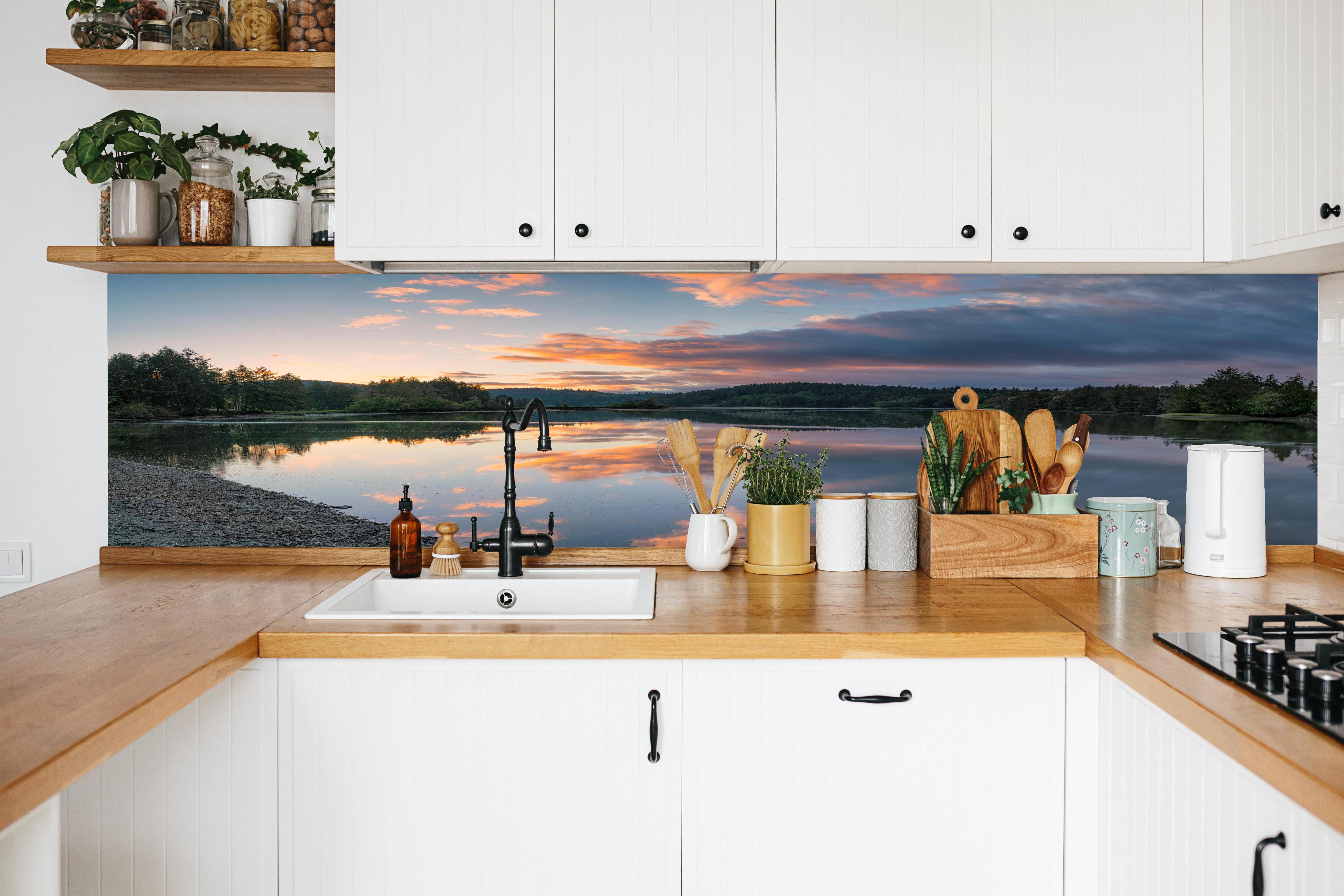 Küche - Spiegelnder See im Sonnenuntergang in weißer Küche hinter Gewürzen und Kochlöffeln aus Holz