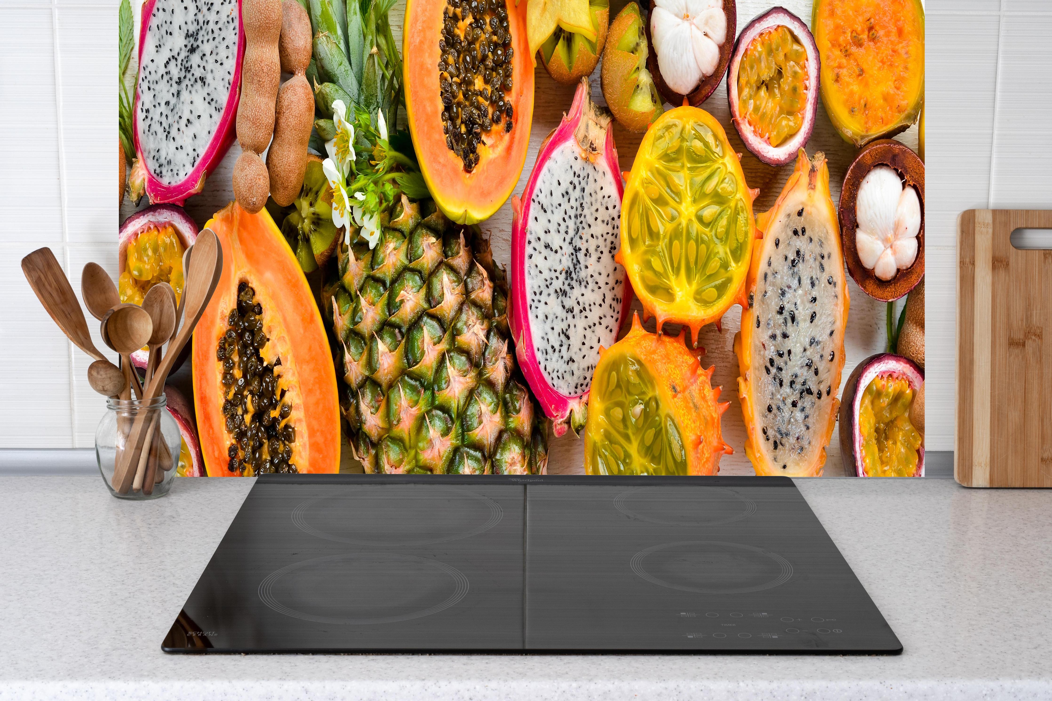 Küche - Tropische Früchte Collage Orange Gelb hinter Cerankochfeld und Holz-Kochutensilien