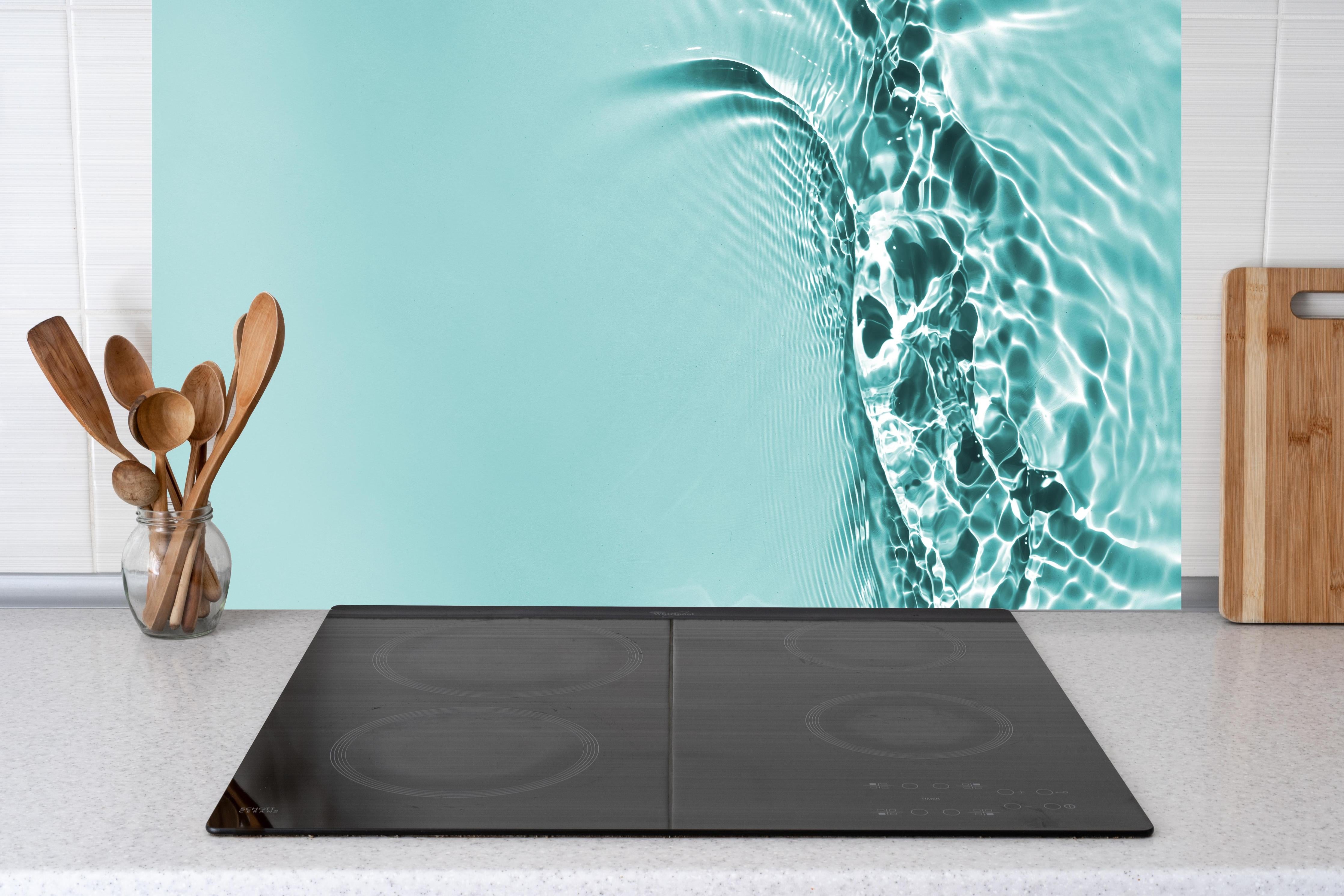 Küche - Türkisblaues Wasser mit Lichtreflexen hinter Cerankochfeld und Holz-Kochutensilien