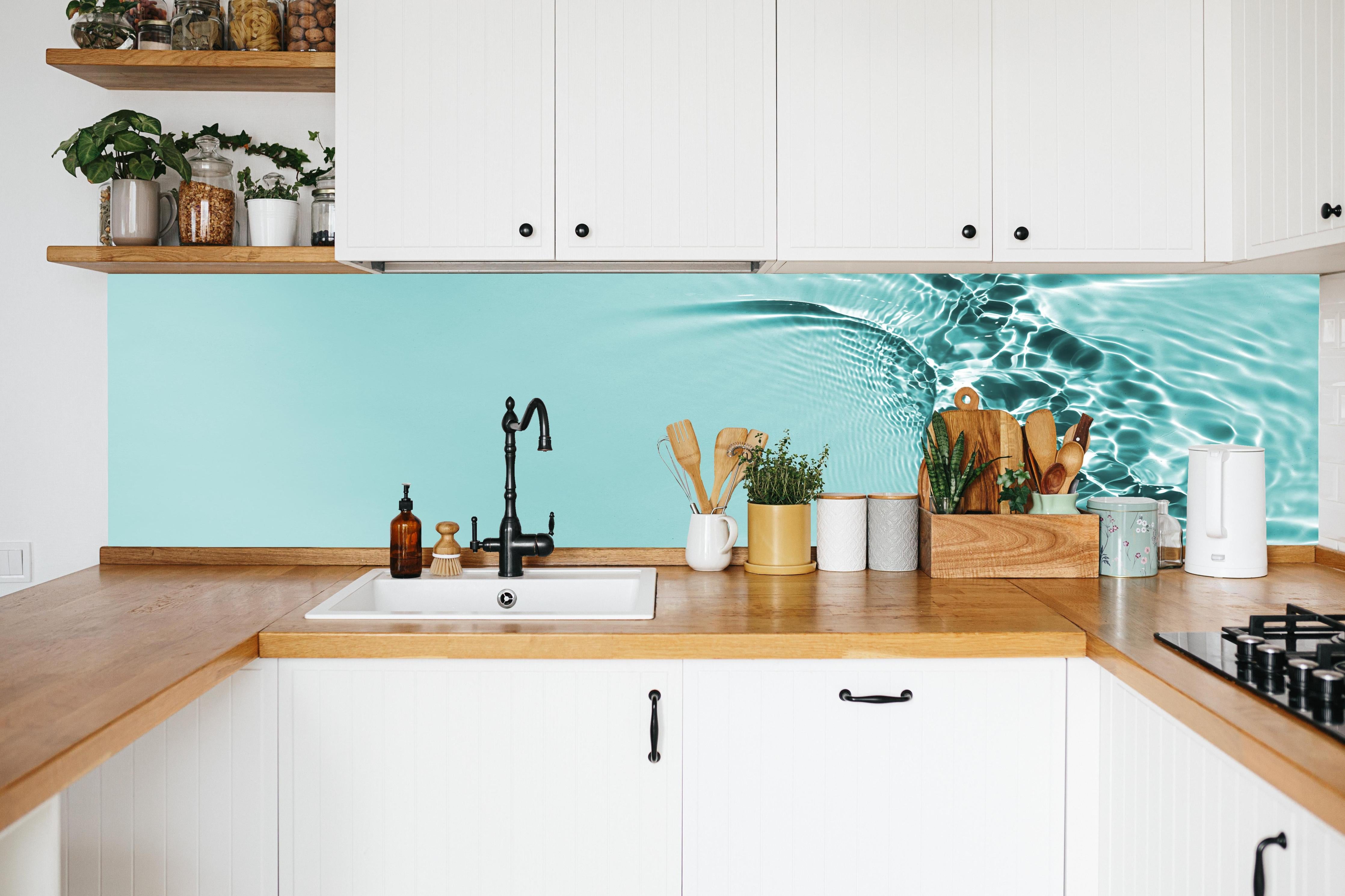 Küche - Türkisblaues Wasser mit Lichtreflexen in weißer Küche hinter Gewürzen und Kochlöffeln aus Holz