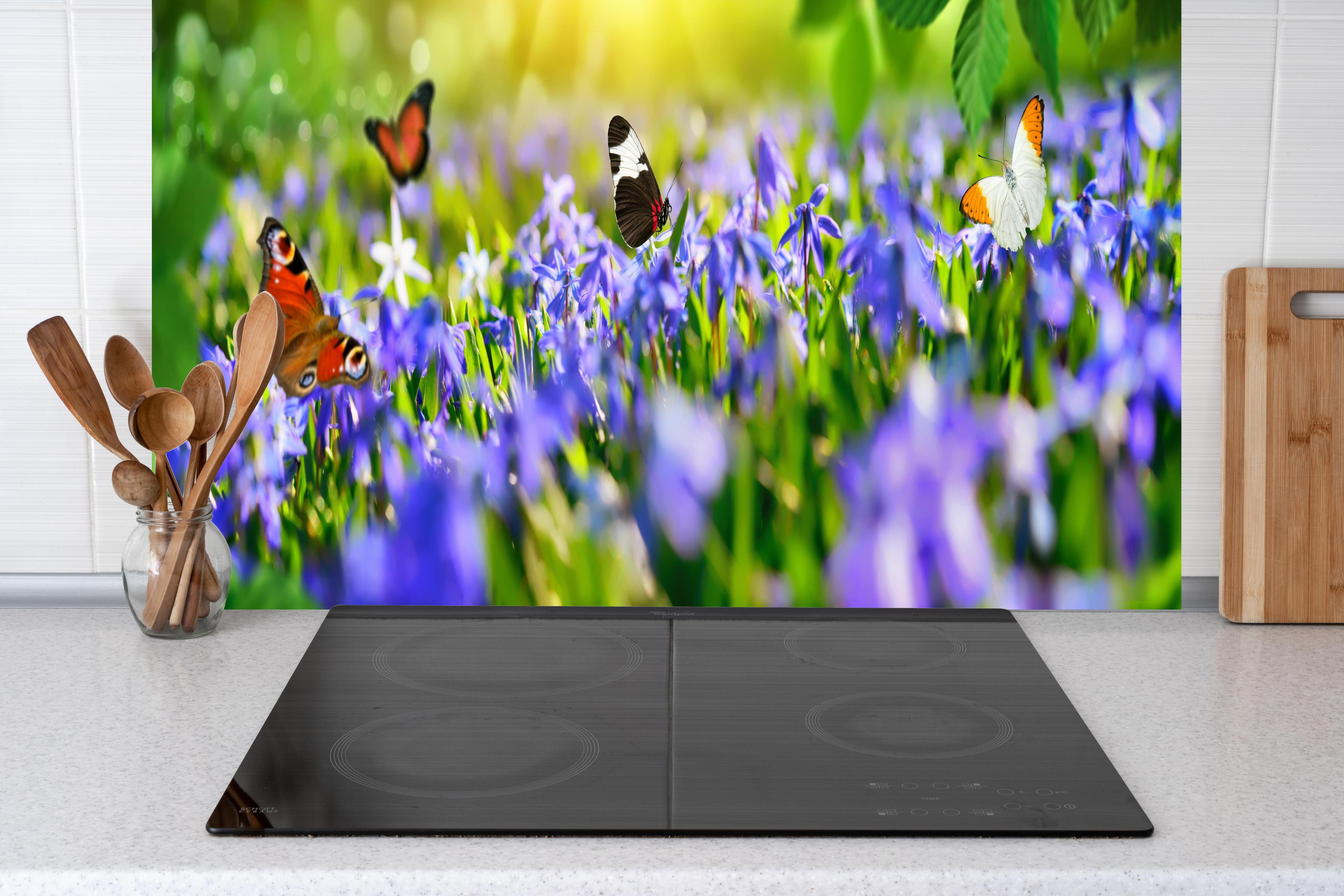 Küche - Violette Blumenwiese mit Schmetterlingen hinter Cerankochfeld und Holz-Kochutensilien
