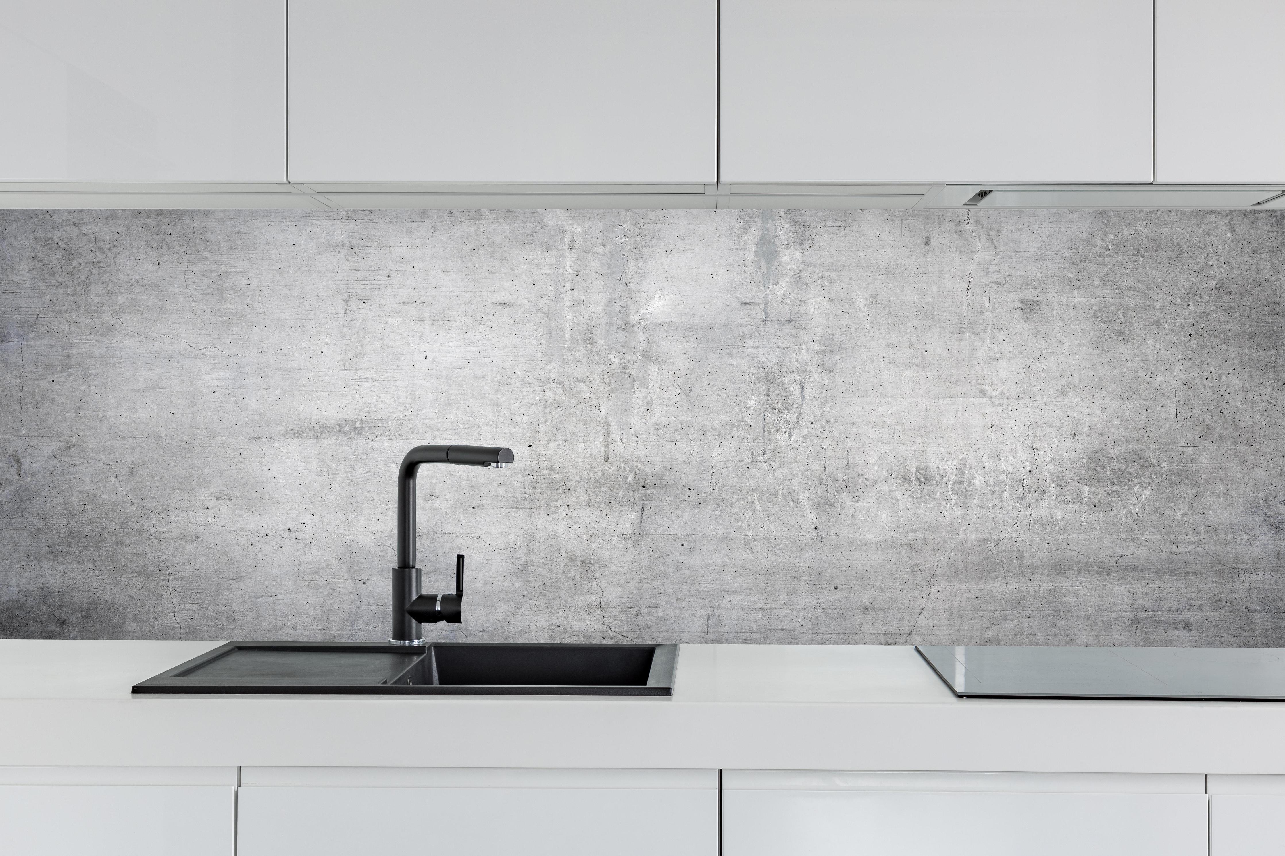 Küche - Weiß-Grau Betonwand-Textur hinter weißen Hochglanz-Küchenregalen und schwarzem Wasserhahn