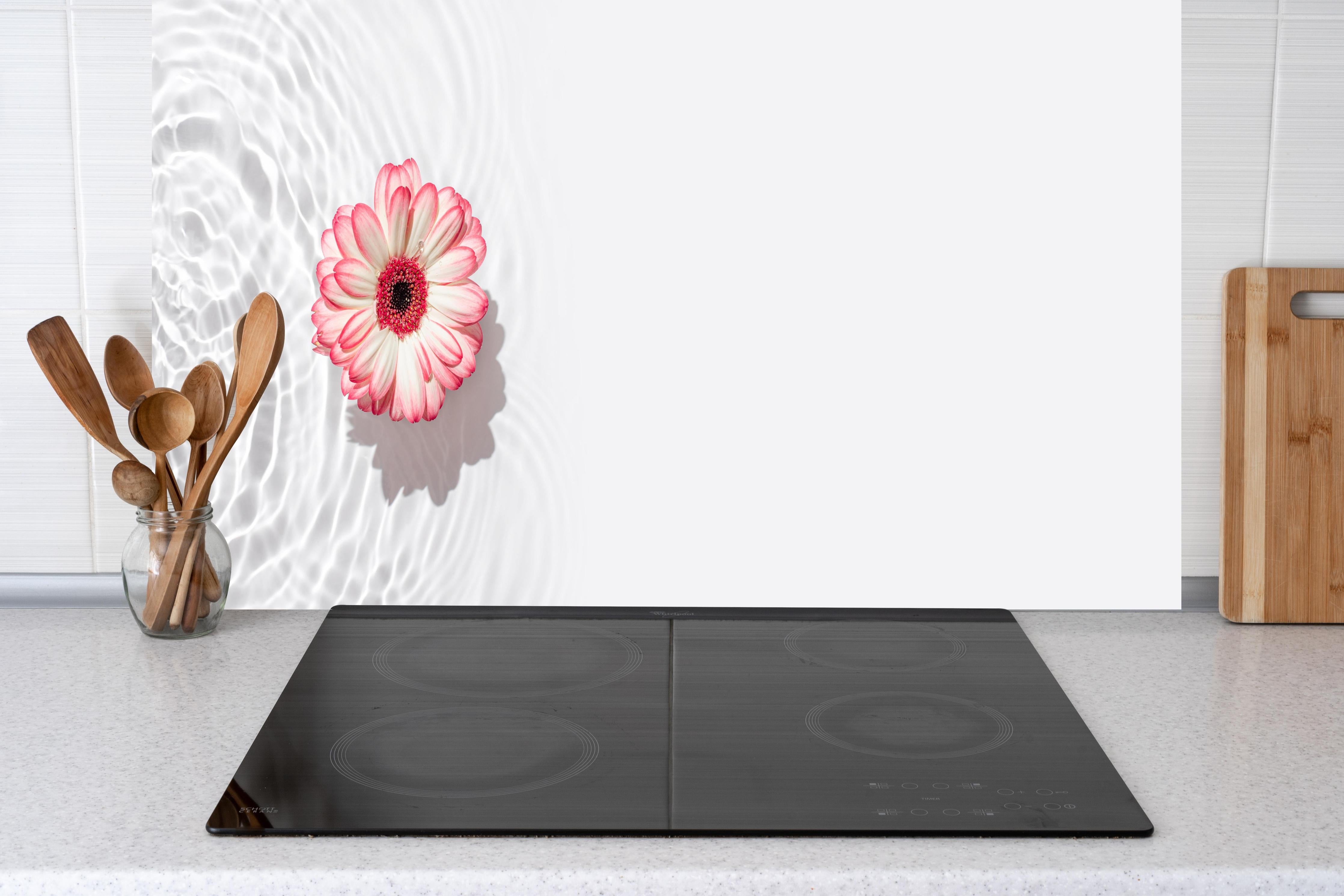 Küche - Weiß-Grau mit Rosa Gerbera hinter Cerankochfeld und Holz-Kochutensilien