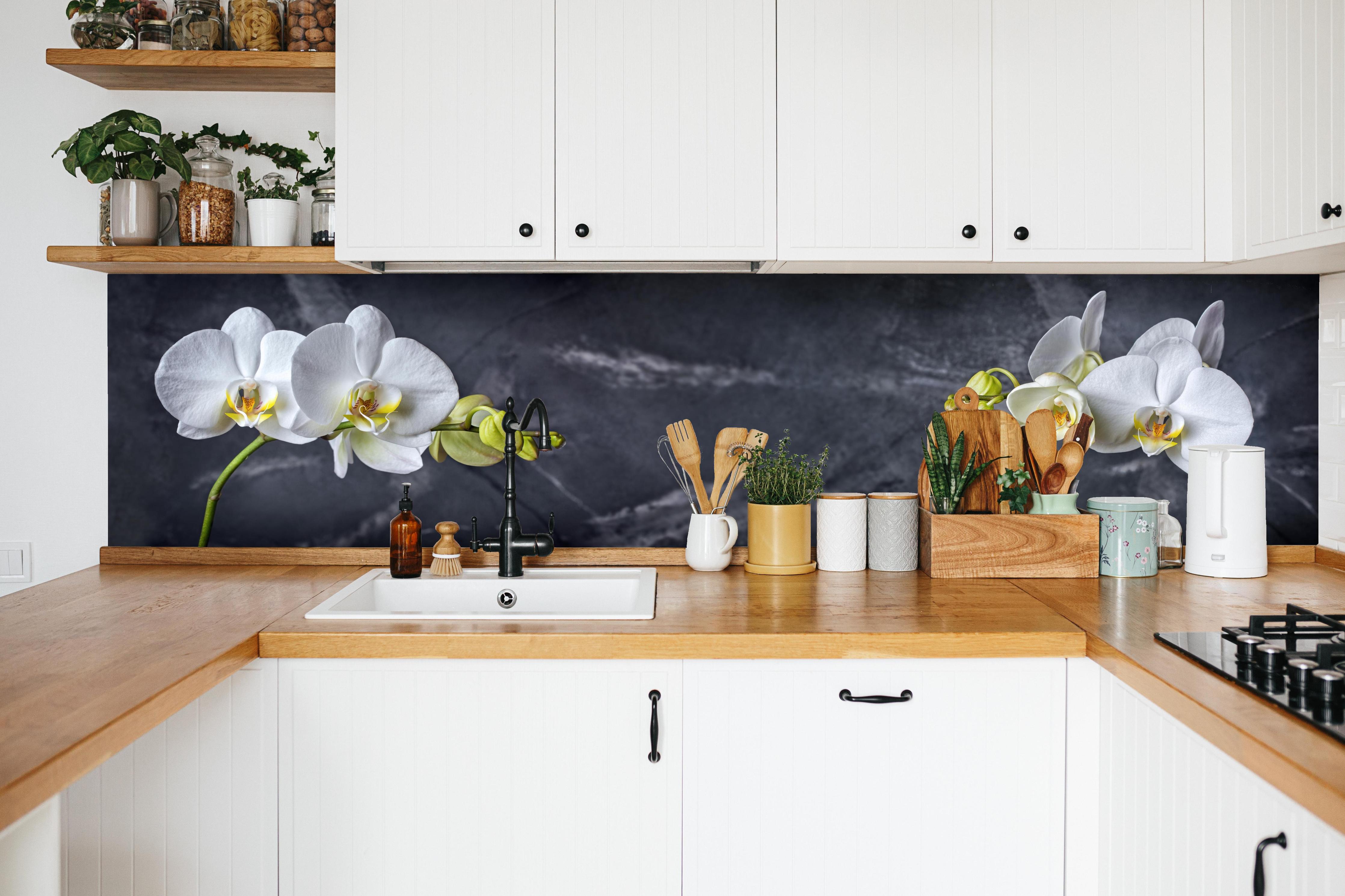 Küche - Weiße Orchideen auf Marmor in weißer Küche hinter Gewürzen und Kochlöffeln aus Holz