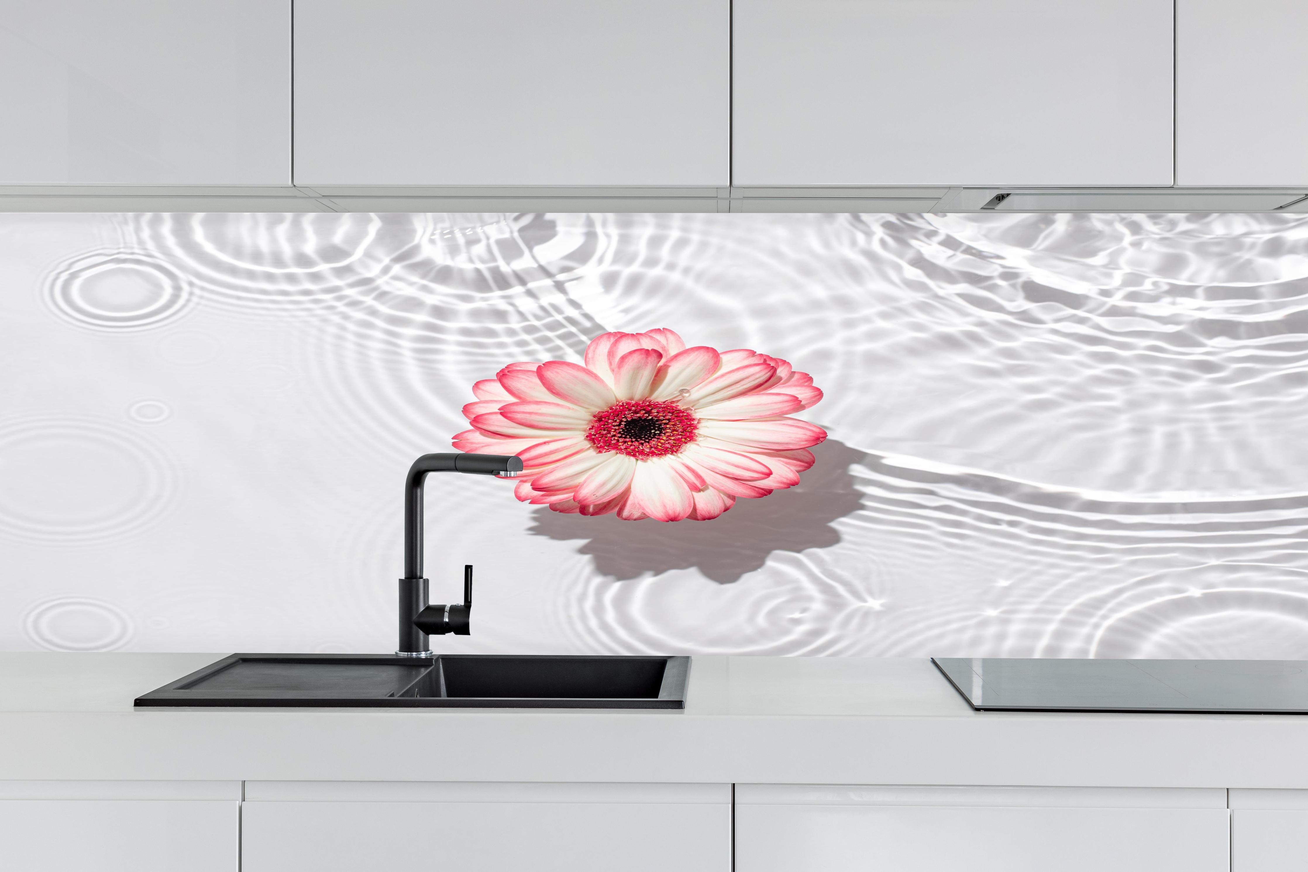 Küche - Weiße Wasserblume in Rosa hinter weißen Hochglanz-Küchenregalen und schwarzem Wasserhahn