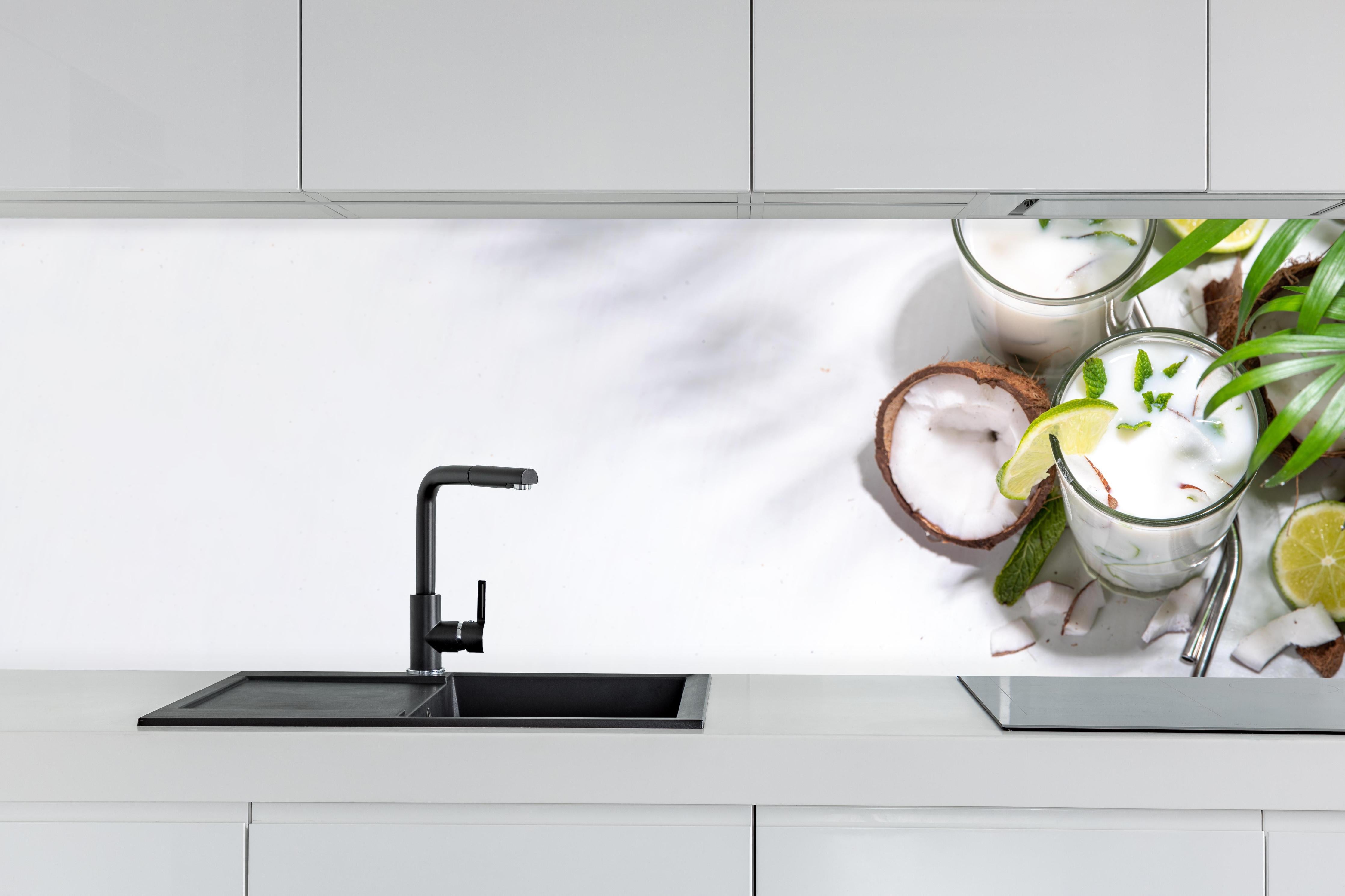 Küche - Weißer Kokosdrink mit Limette hinter weißen Hochglanz-Küchenregalen und schwarzem Wasserhahn