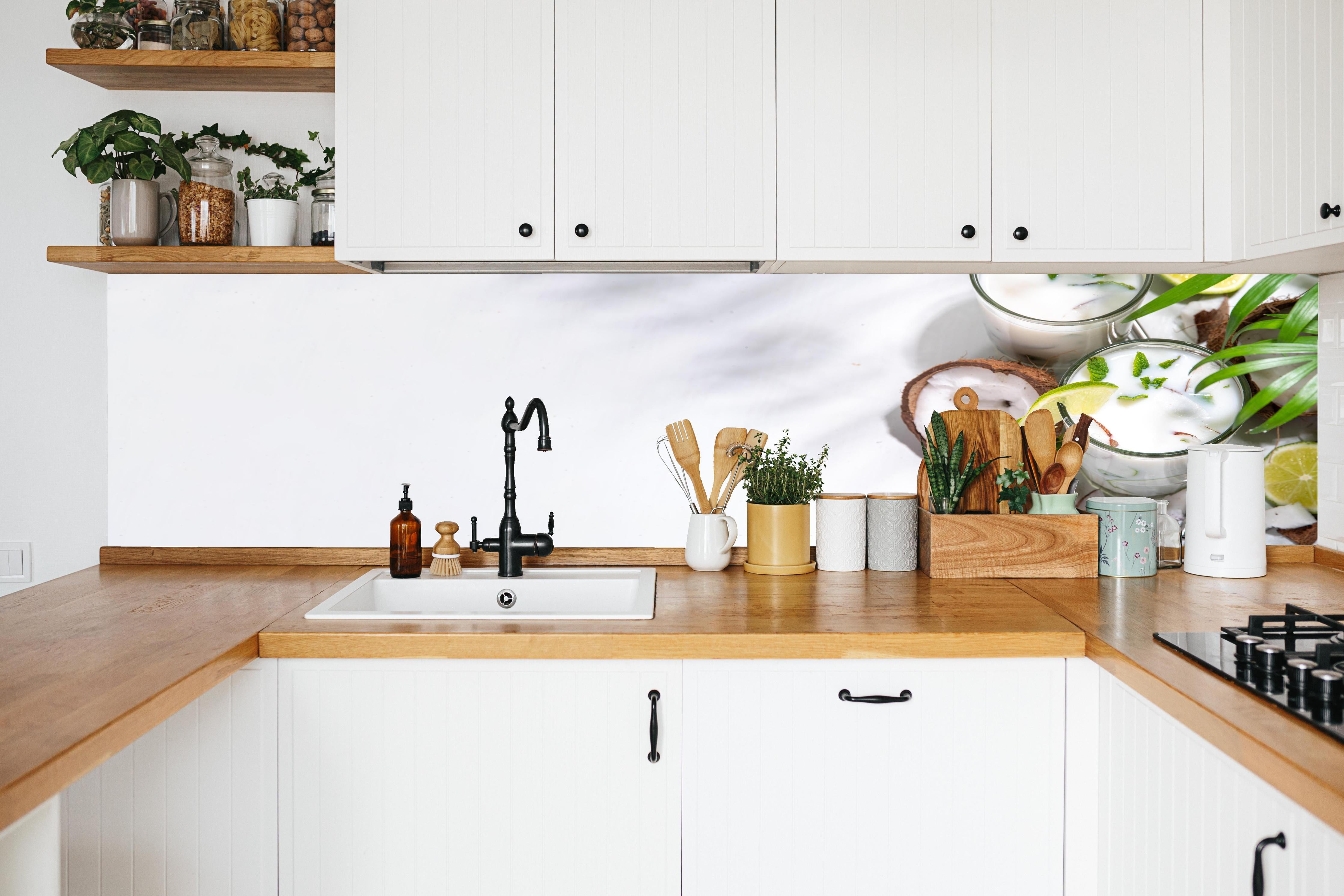 Küche - Weißer Kokosdrink mit Limette in weißer Küche hinter Gewürzen und Kochlöffeln aus Holz