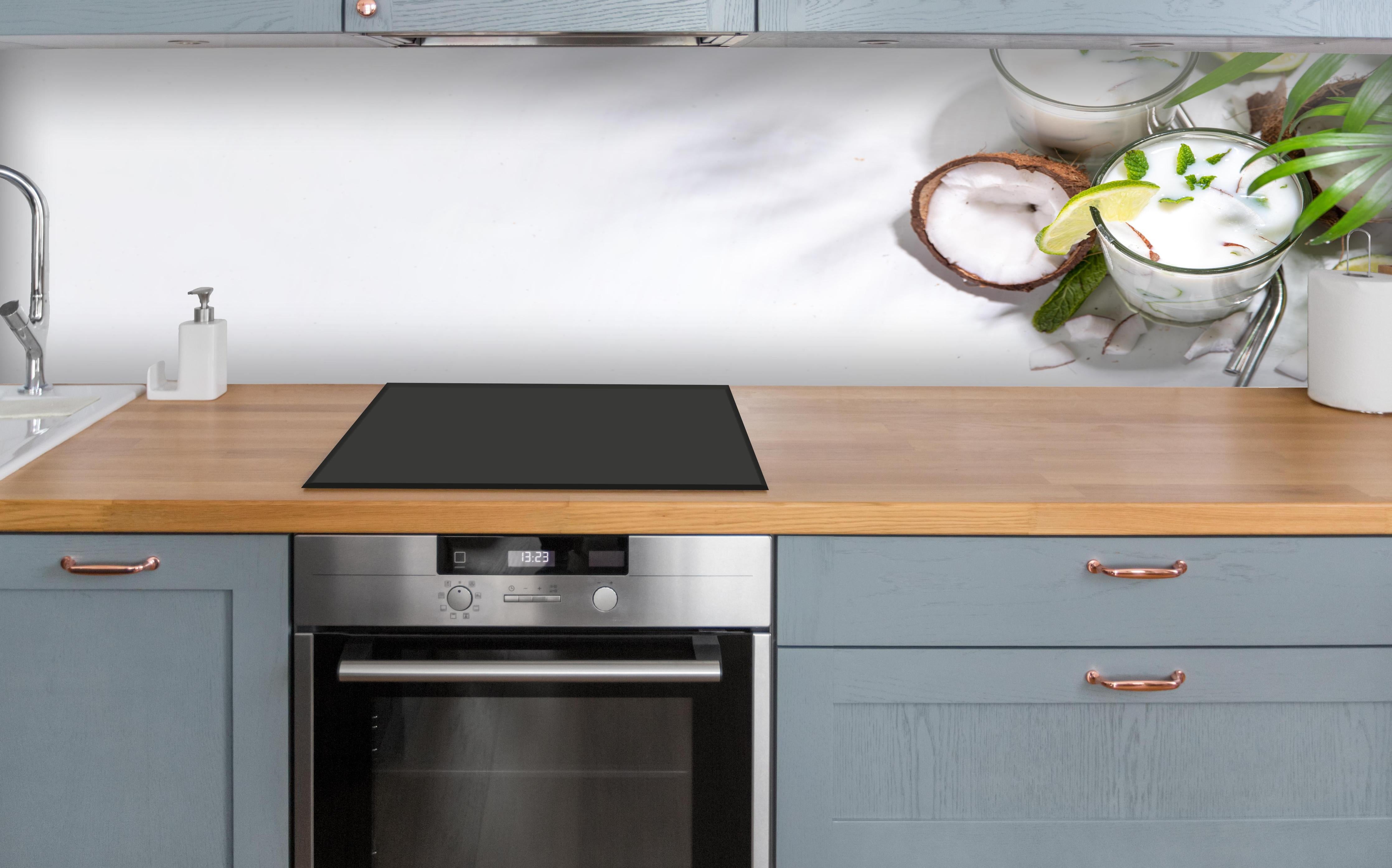 Küche - Weißer Kokosdrink mit Limette über polierter Holzarbeitsplatte mit Cerankochfeld