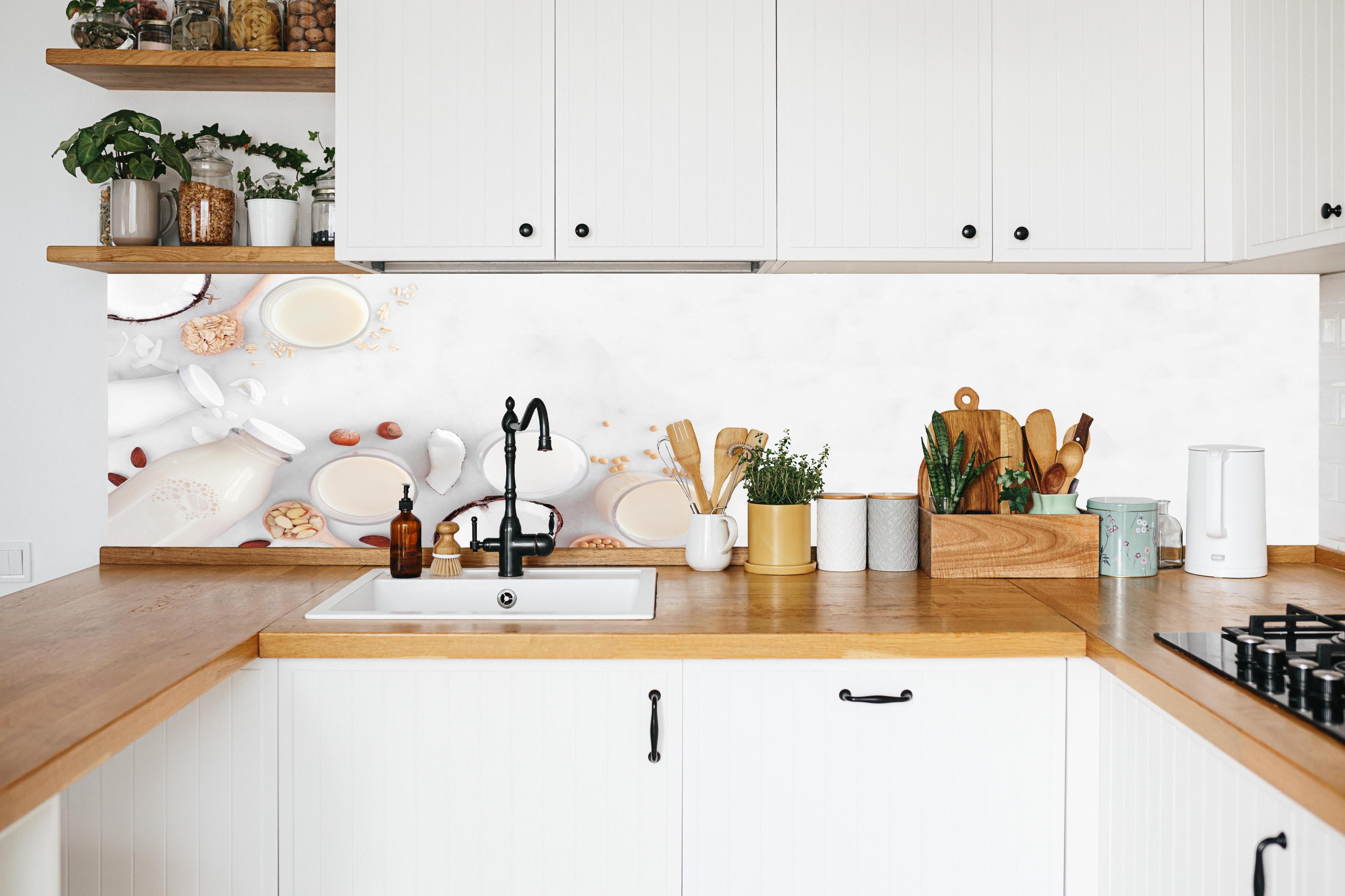 Küche - Weißes Pflanzenmilch-Stillleben in weißer Küche hinter Gewürzen und Kochlöffeln aus Holz