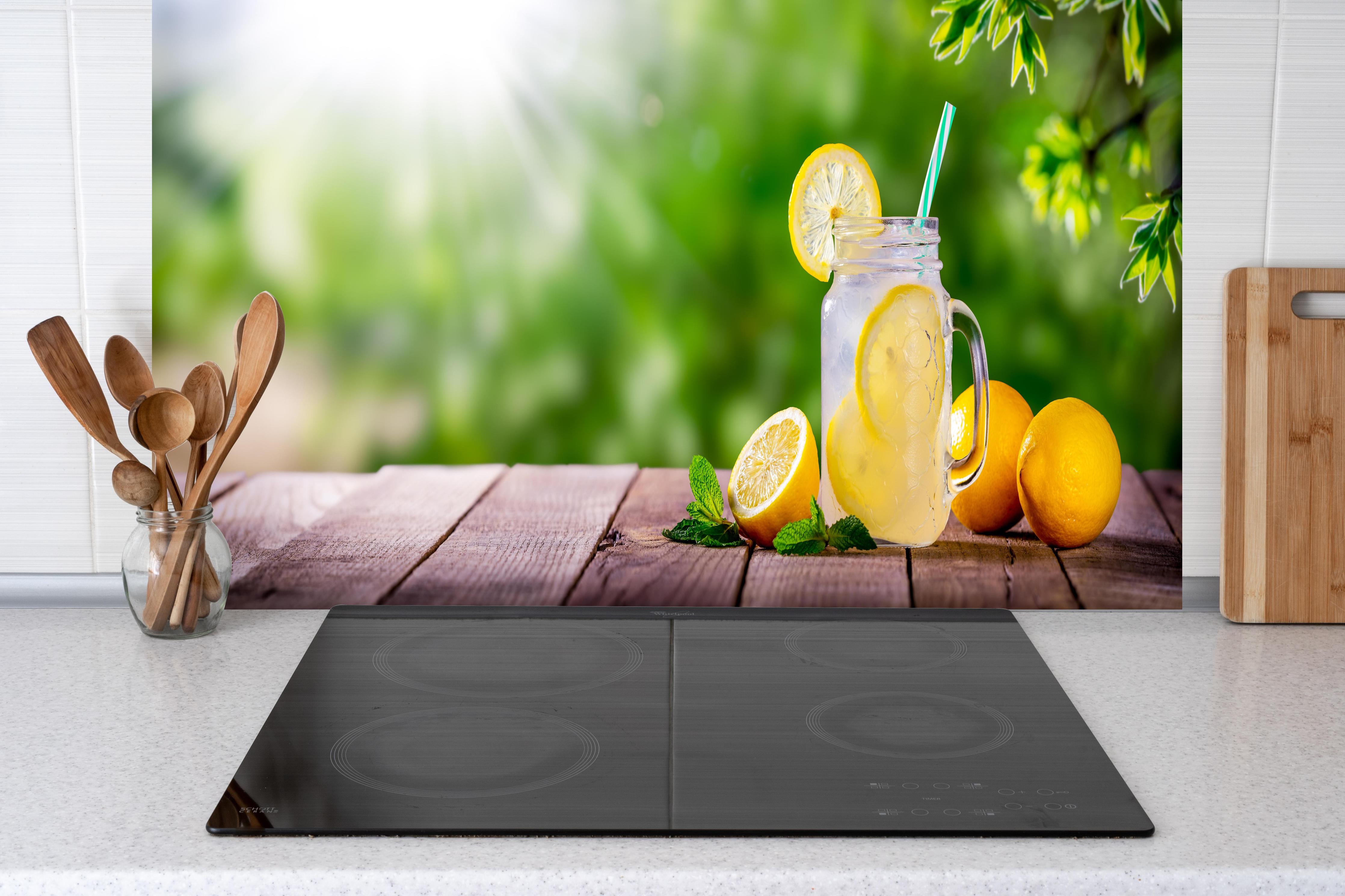 Küche - Zitronen-Limonade auf Holztisch hinter Cerankochfeld und Holz-Kochutensilien