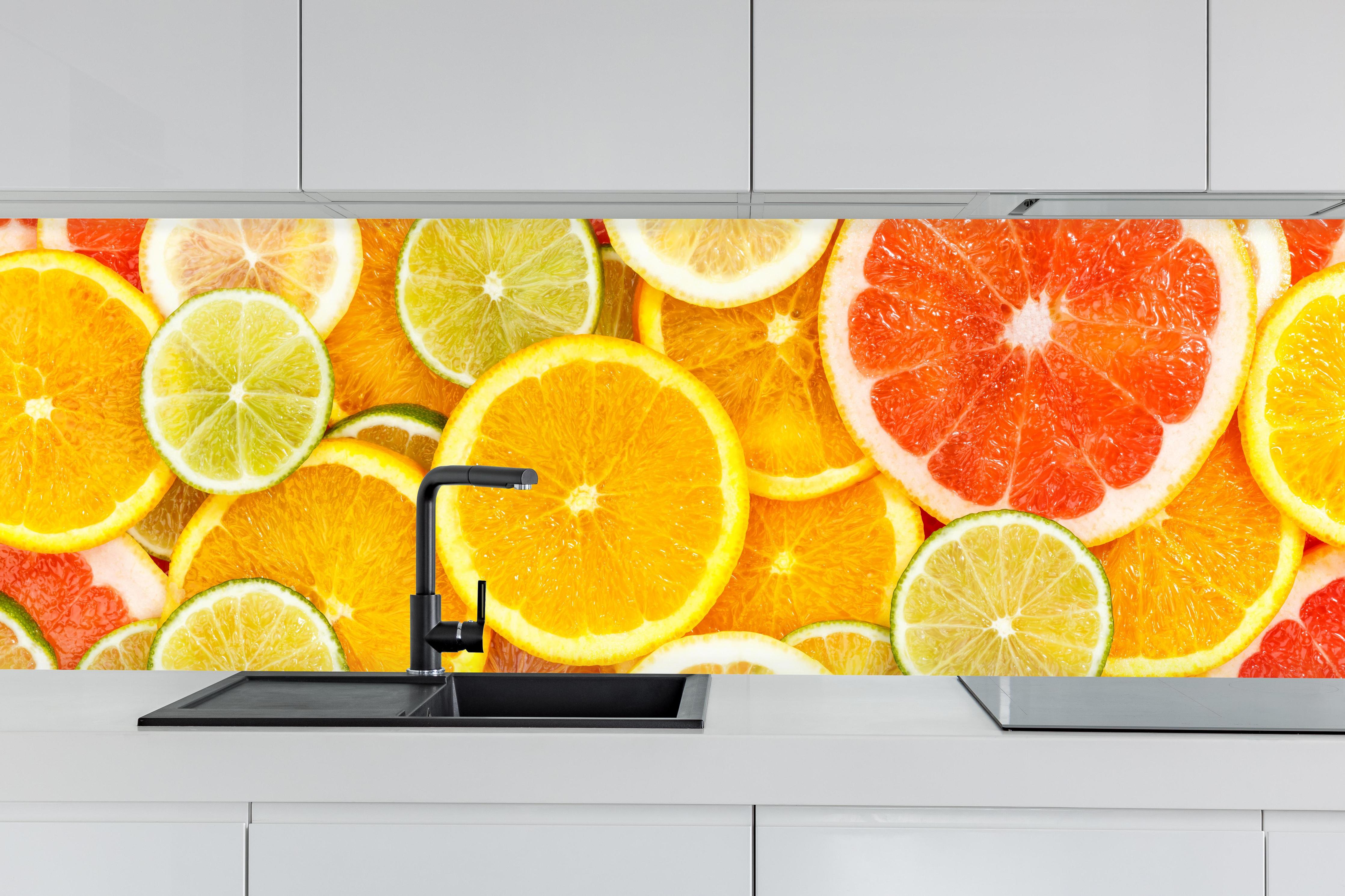 Küche - Zitrusmix Orange Gelb Grün hinter weißen Hochglanz-Küchenregalen und schwarzem Wasserhahn