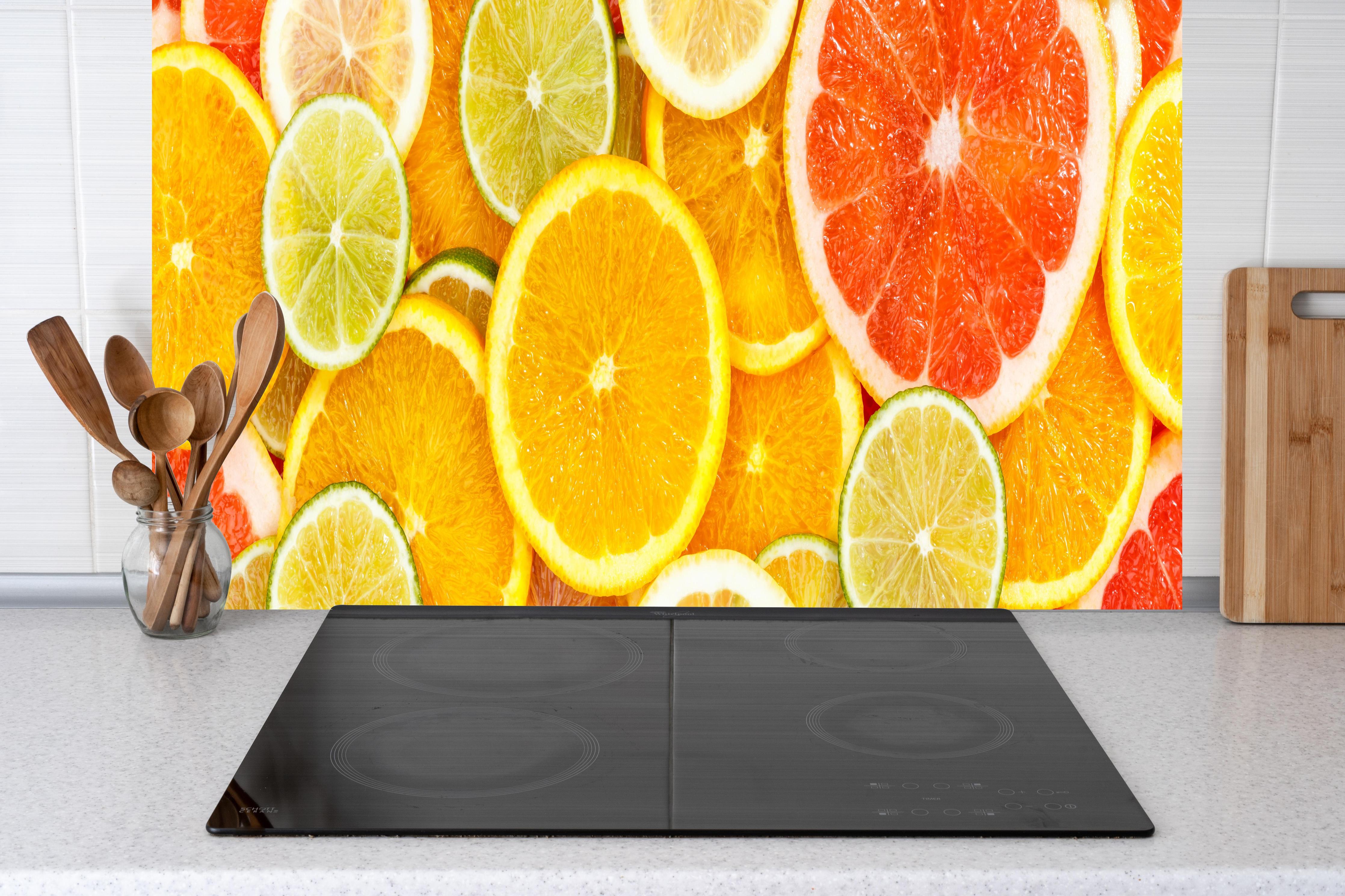 Küche - Zitrusmix Orange Gelb Grün hinter Cerankochfeld und Holz-Kochutensilien