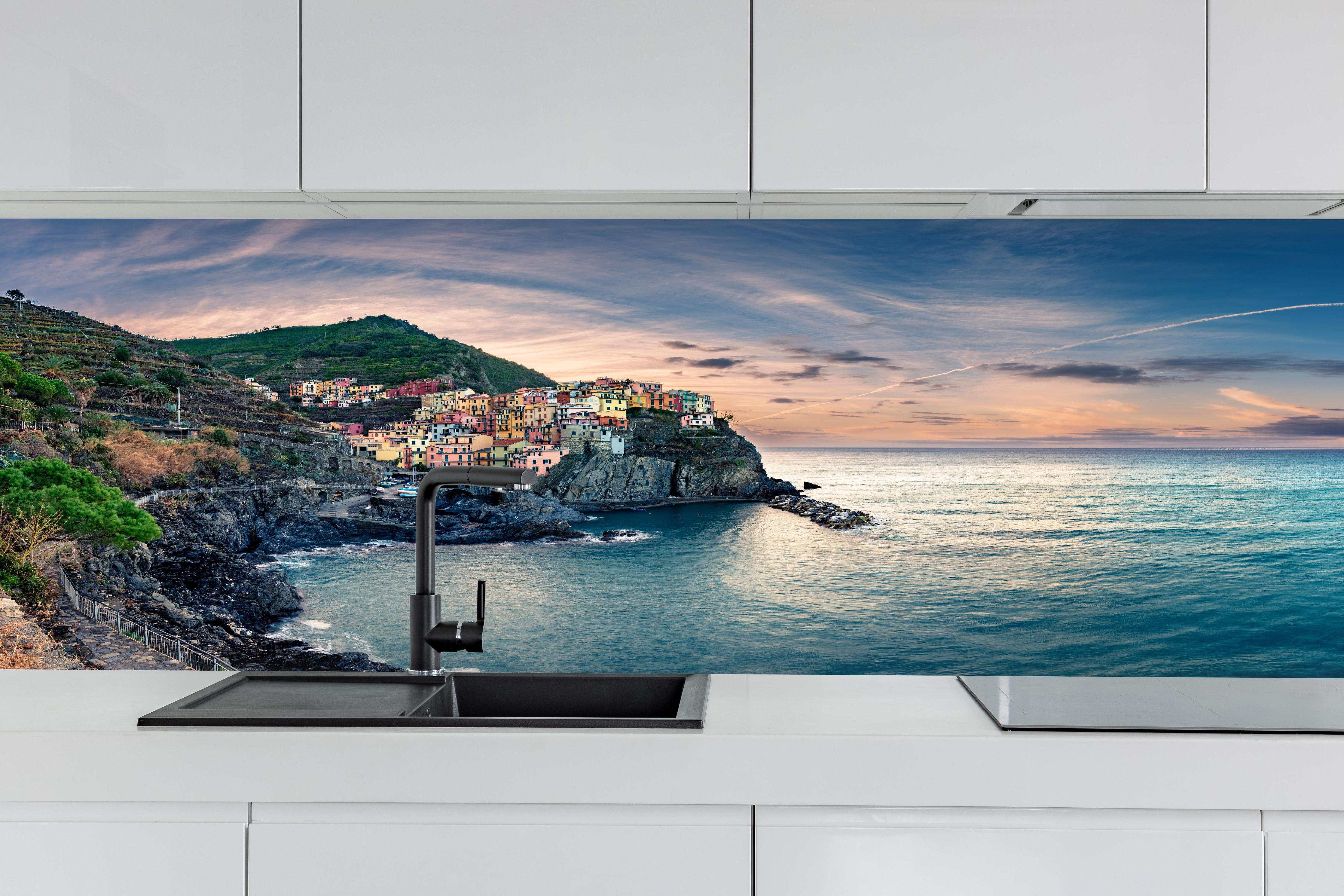 Küche - talienische Küste im Abendrot hinter weißen Hochglanz-Küchenregalen und schwarzem Wasserhahn