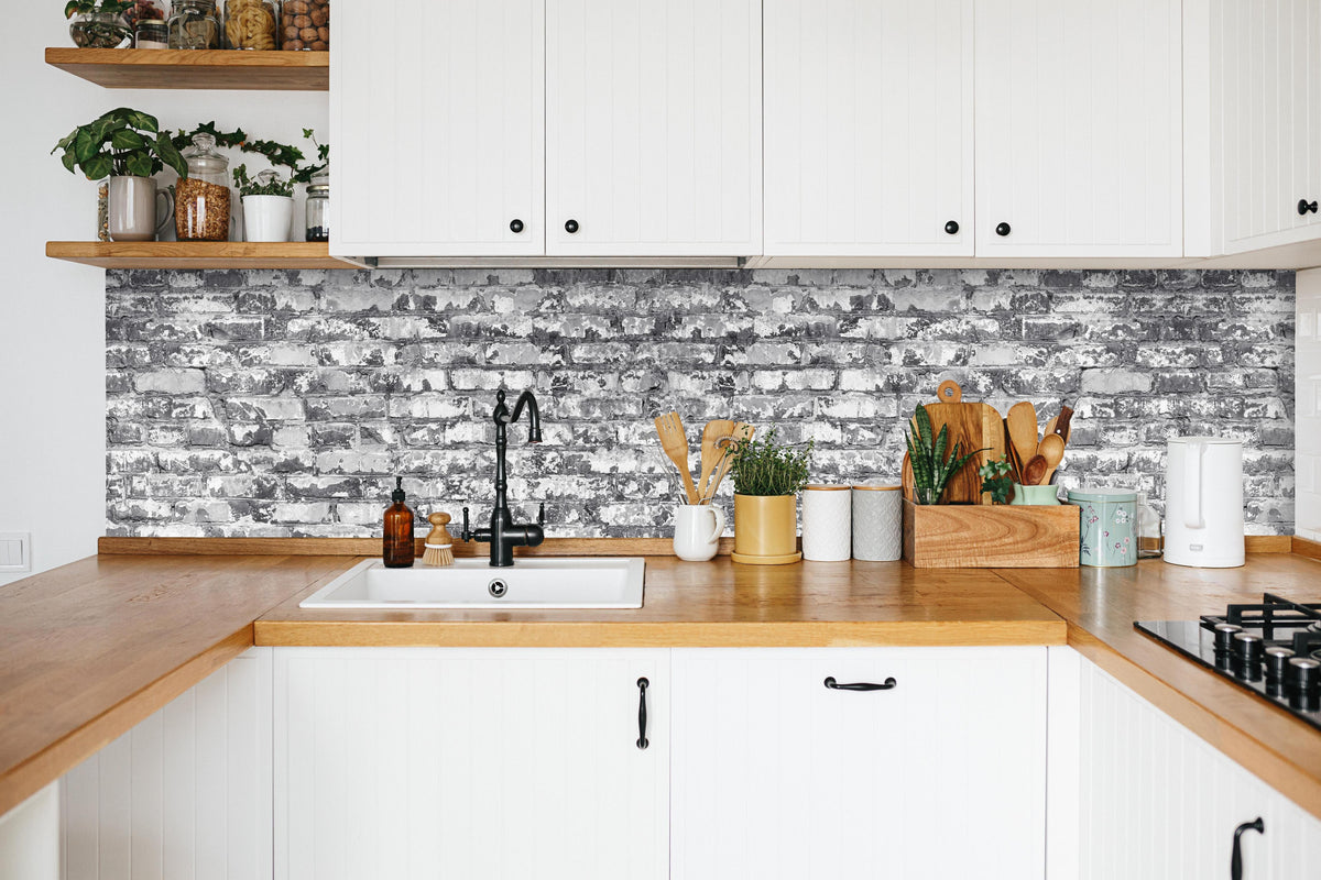 Küche -  Hellgraue verwitterte Vintage  Ziegelwand in weißer Küche hinter Gewürzen und Kochlöffeln aus Holz