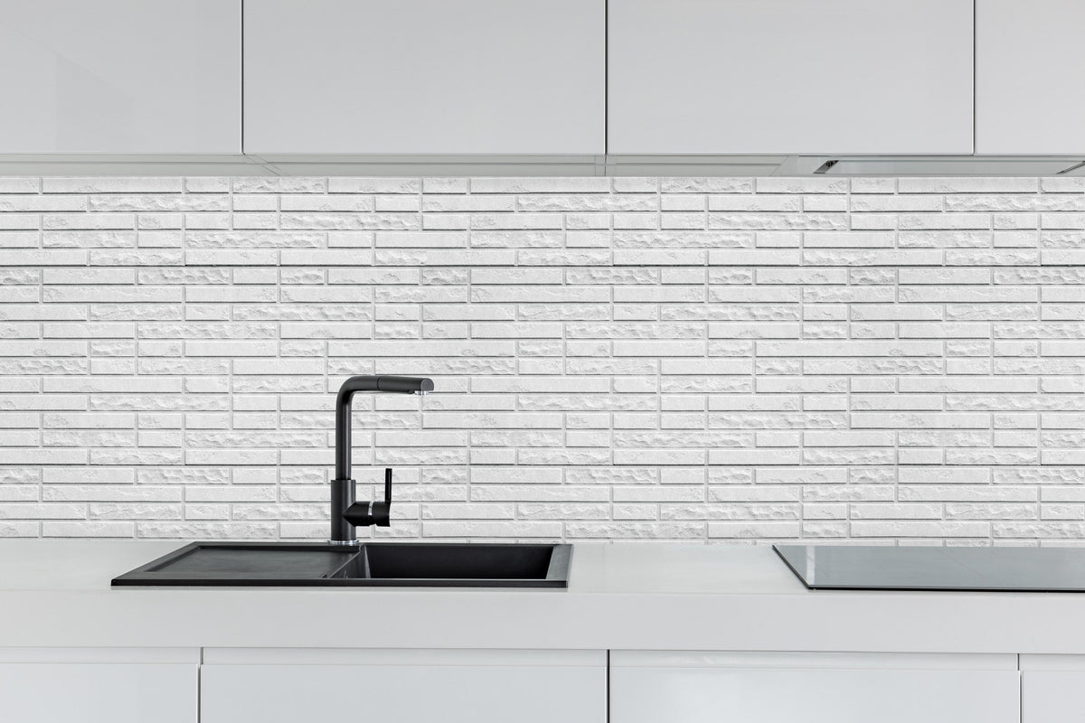 Küche - Abstrakte weiße Backsteinmauer hinter weißen Hochglanz-Küchenregalen und schwarzem Wasserhahn