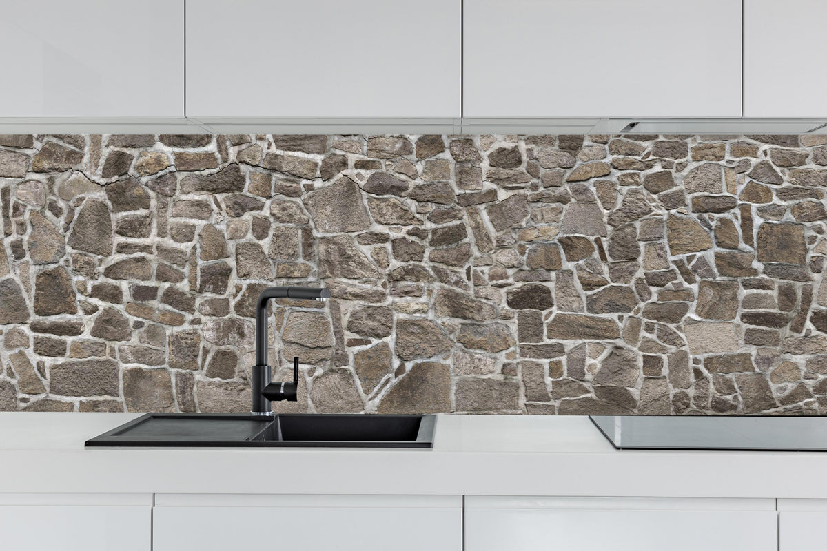 Küche - Alte Steinmauer hinter weißen Hochglanz-Küchenregalen und schwarzem Wasserhahn