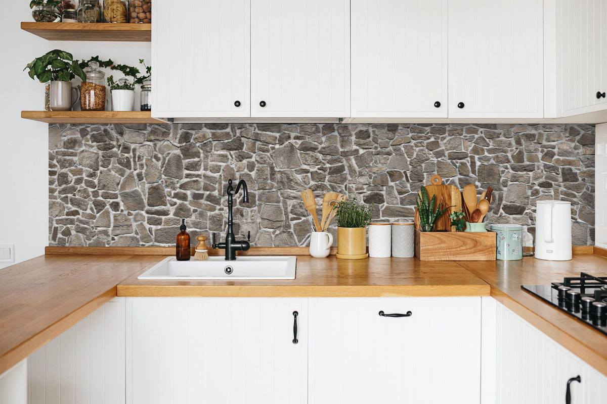 Küche - Alte Steinmauer in weißer Küche hinter Gewürzen und Kochlöffeln aus Holz