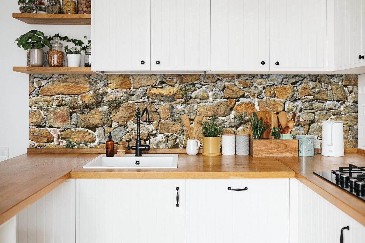 Küche - Alte unverputzte Burgmauer in weißer Küche hinter Gewürzen und Kochlöffeln aus Holz