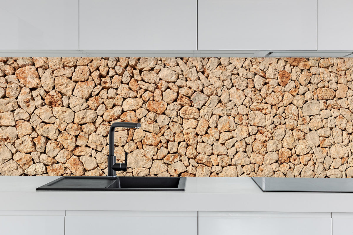 Küche - Bräunliche Panorama-Textur Steinmauer hinter weißen Hochglanz-Küchenregalen und schwarzem Wasserhahn