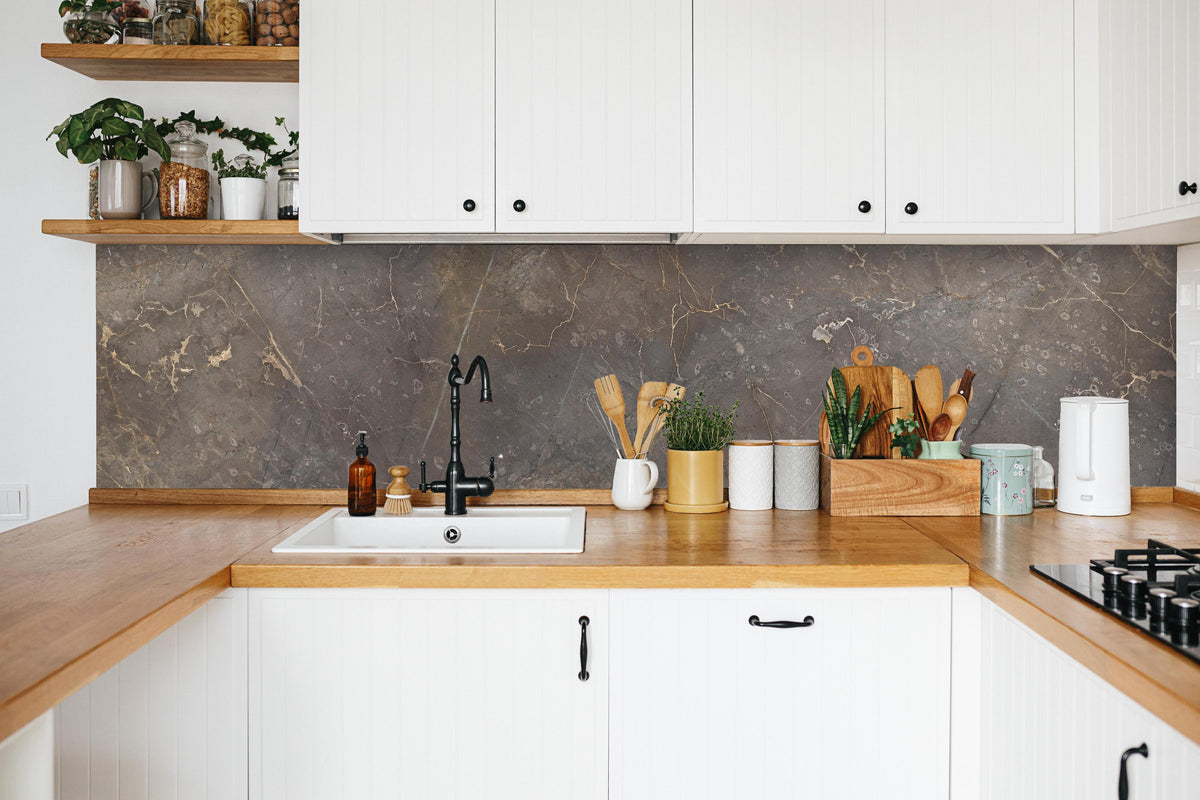 Küche - Braun-Grauer Marmor mit Adern in weißer Küche hinter Gewürzen und Kochlöffeln aus Holz