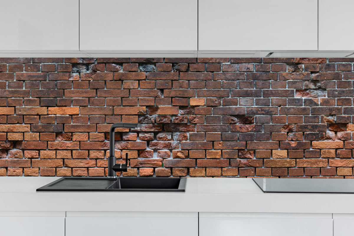 Küche - Braune kaputte Ziegelsteinwand hinter weißen Hochglanz-Küchenregalen und schwarzem Wasserhahn