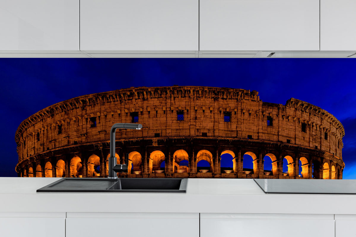Küche - Das Kolosseum bei Nacht in Rom hinter weißen Hochglanz-Küchenregalen und schwarzem Wasserhahn
