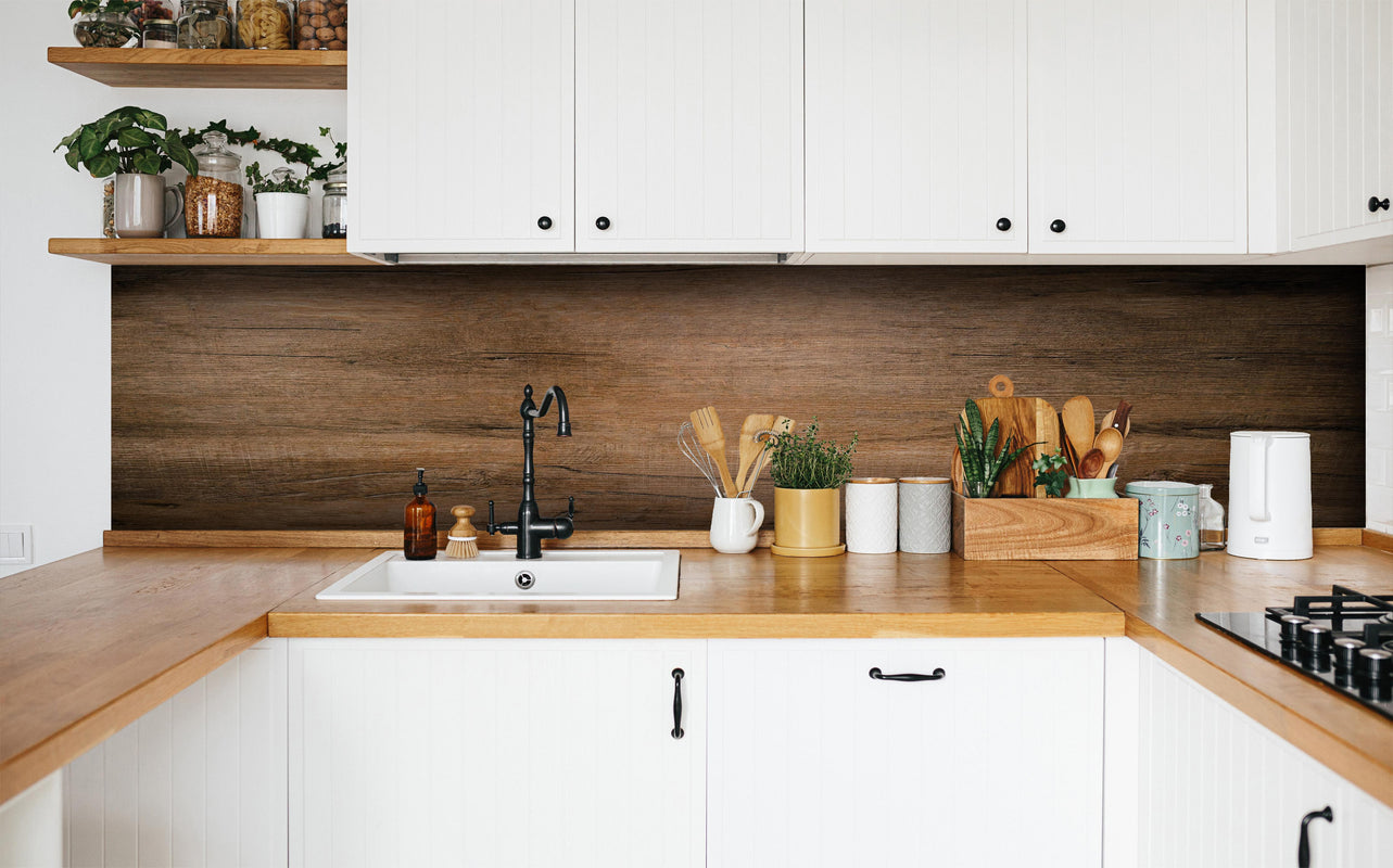Küche - Dunkelbraune Holzplatte in weißer Küche hinter Gewürzen und Kochlöffeln aus Holz
