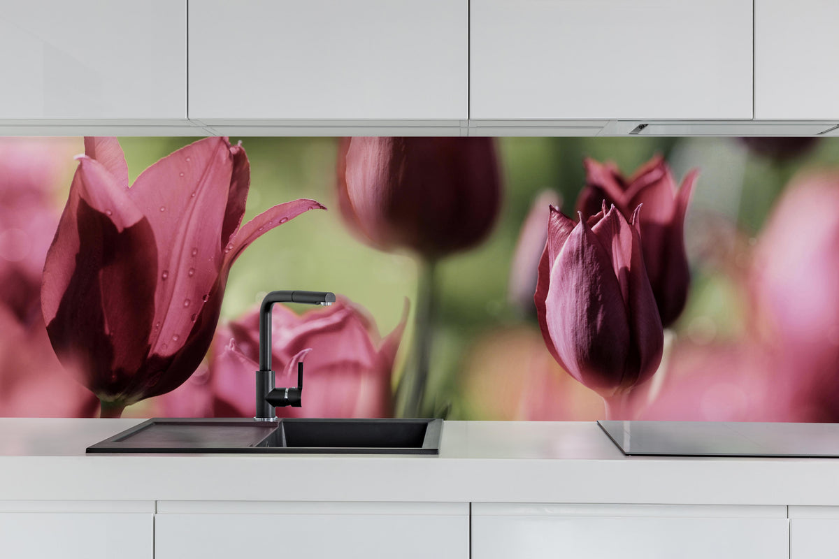 Küche - Dunkelrosa Tulpen hinter weißen Hochglanz-Küchenregalen und schwarzem Wasserhahn