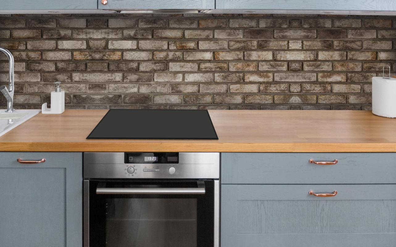 Küche - Dunkle Steinmauer über polierter Holzarbeitsplatte mit Cerankochfeld