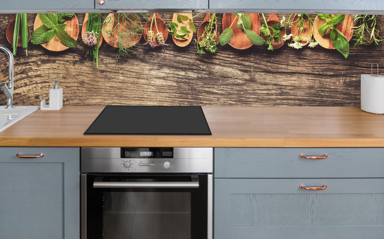 Küche - Frische Kräuter auf Holzplatte über polierter Holzarbeitsplatte mit Cerankochfeld
