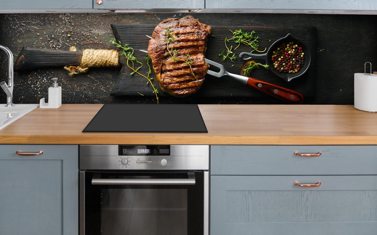 Küche - Gegrilltes Ribeye auf Holzplatte über polierter Holzarbeitsplatte mit Cerankochfeld